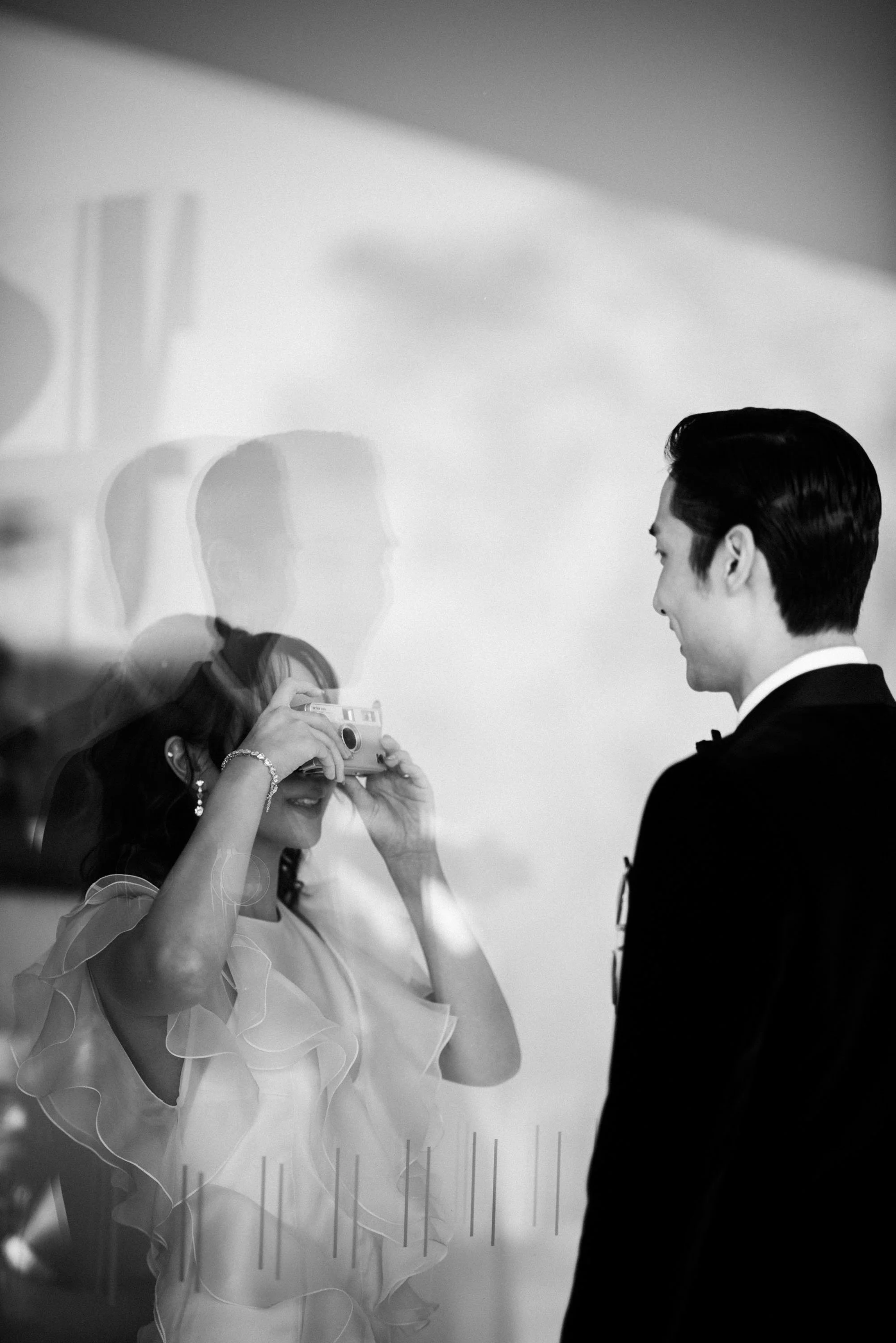 Bride taking a film photograph of the groom before the celebration.