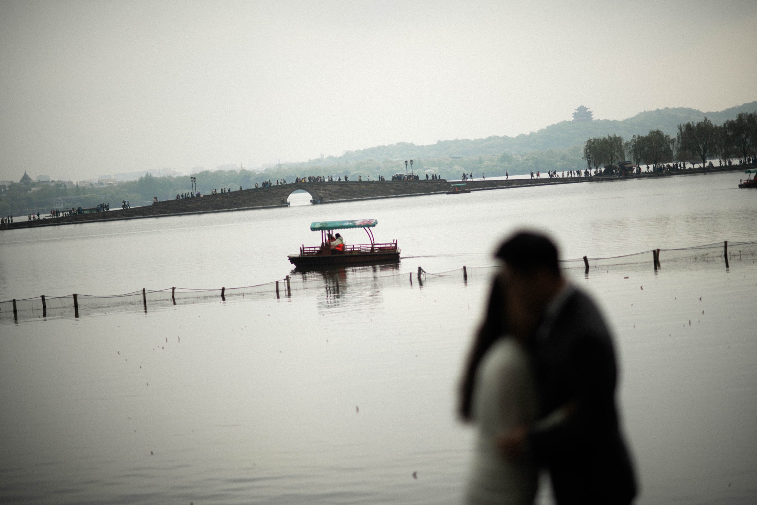 Bride and groom embracing with West Lake in the background.