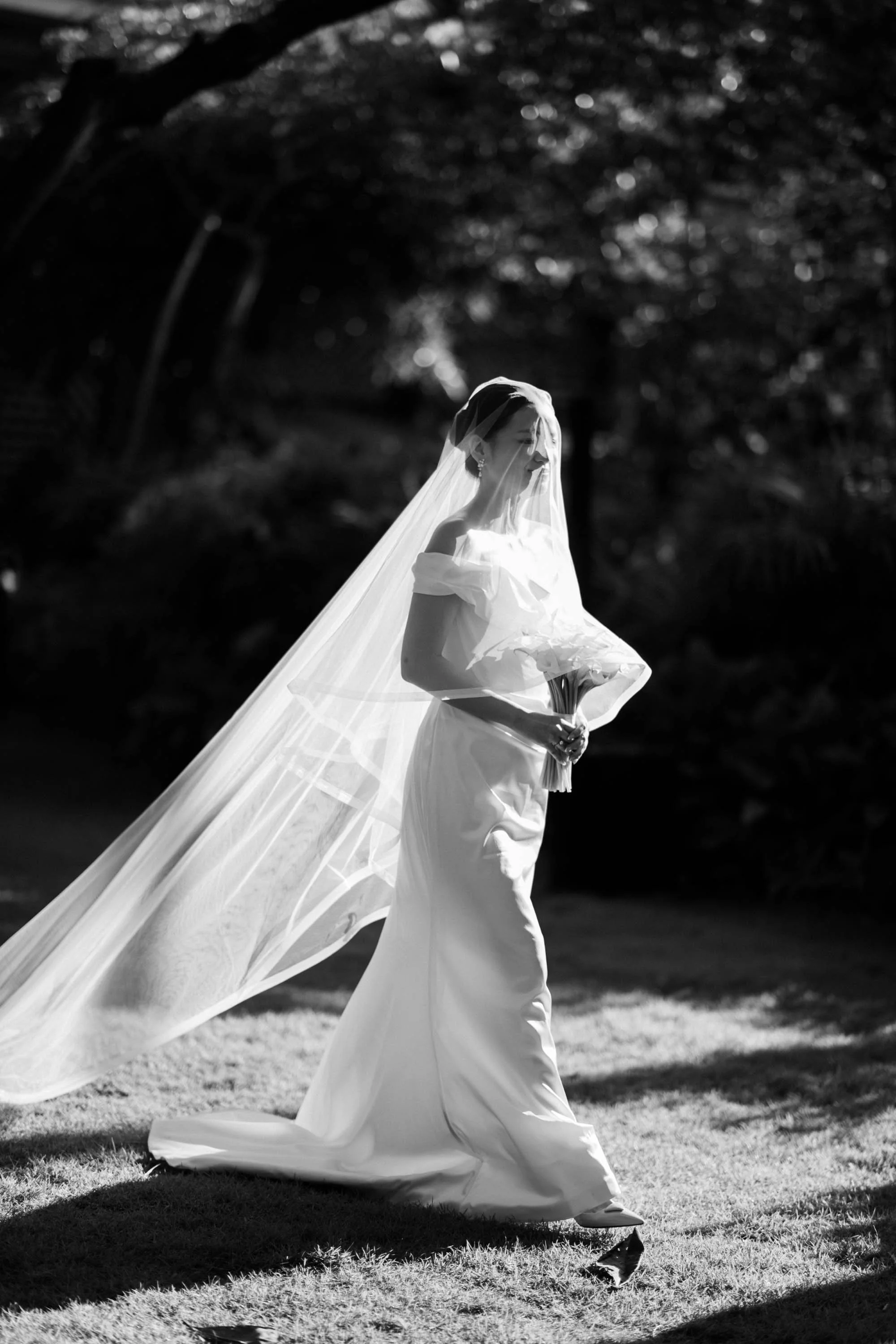 Bride walking toward the ceremony through natural light at Rosewood Phuket.