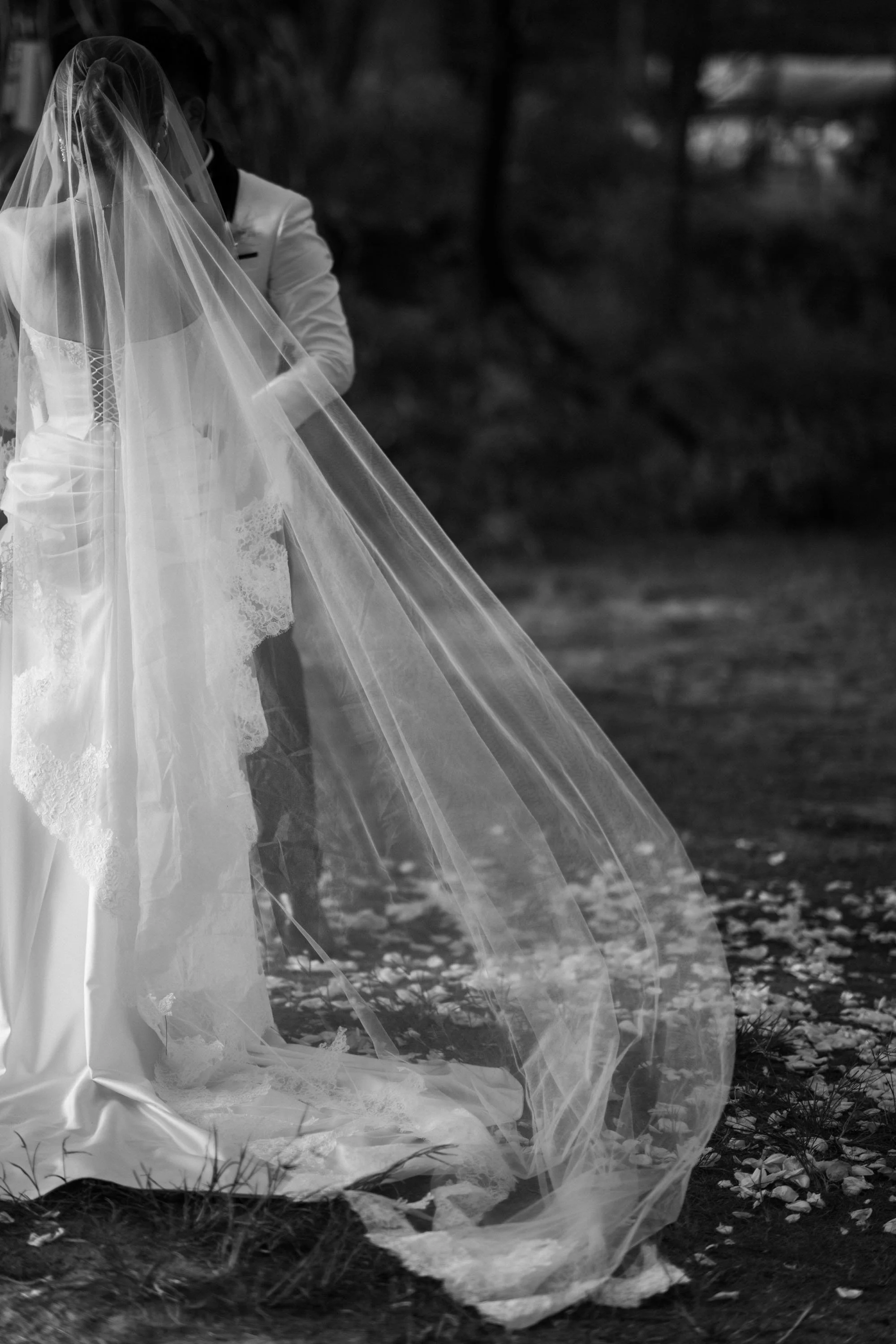 Bride and groom exchanging rings as the bride’s veil catches the breeze.