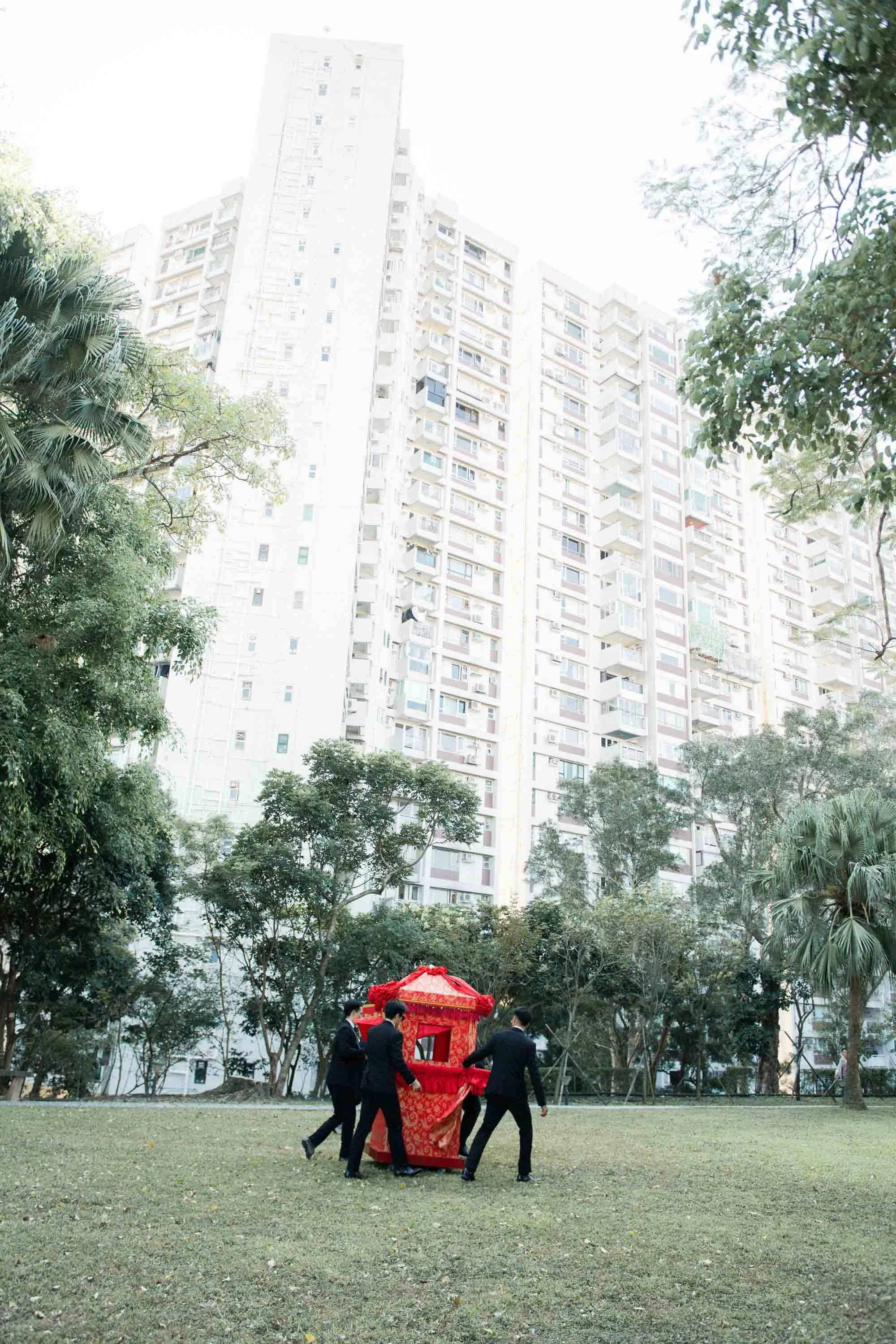 Friends carrying the traditional bridal sedan chair through the garden.