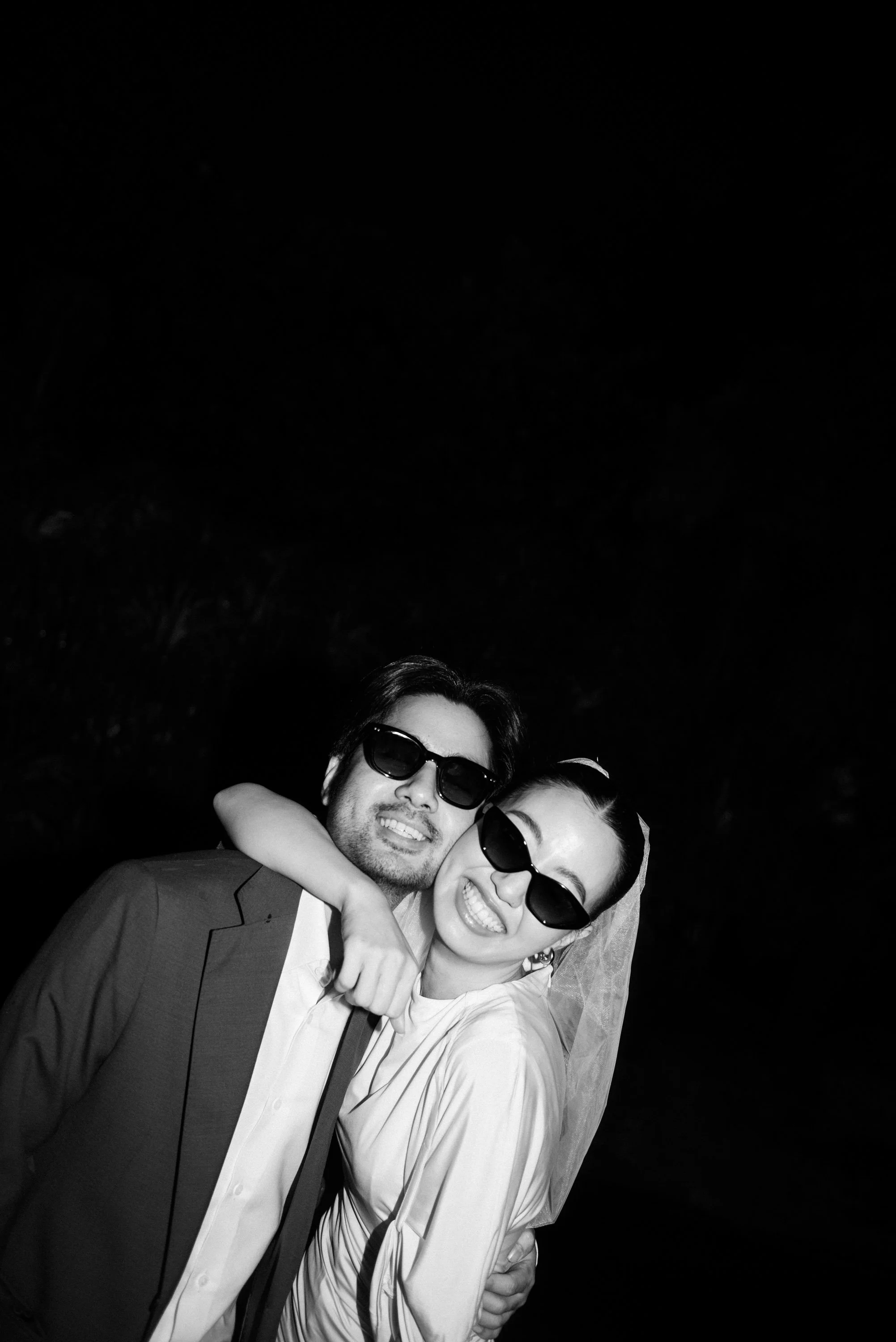Woman playfully wrapping her arm around her partner as they smile at the camera.