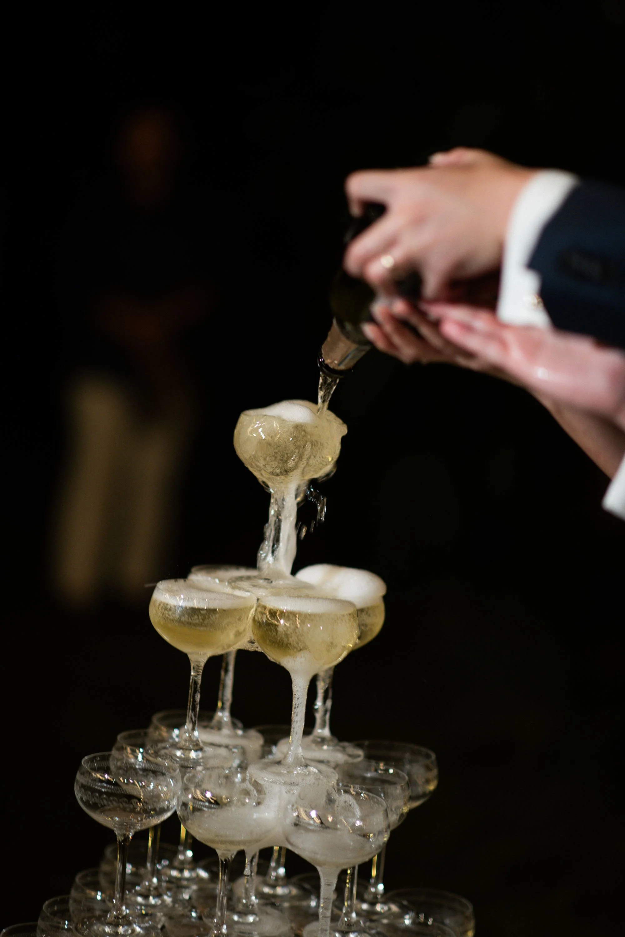 Couple pouring champagne into a champagne tower.