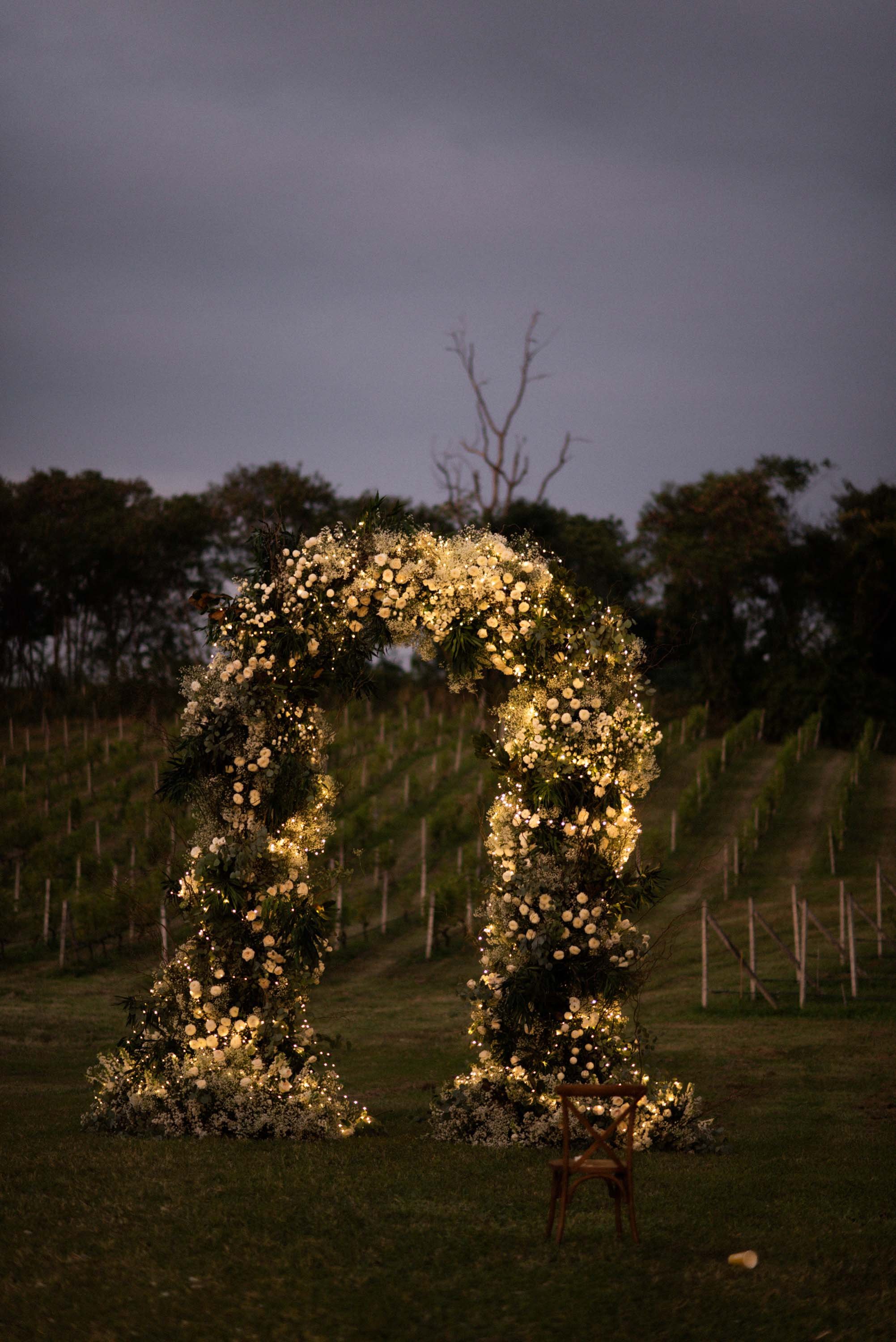 Floral arch from the wedding ceremony illuminated by lights in the evening.