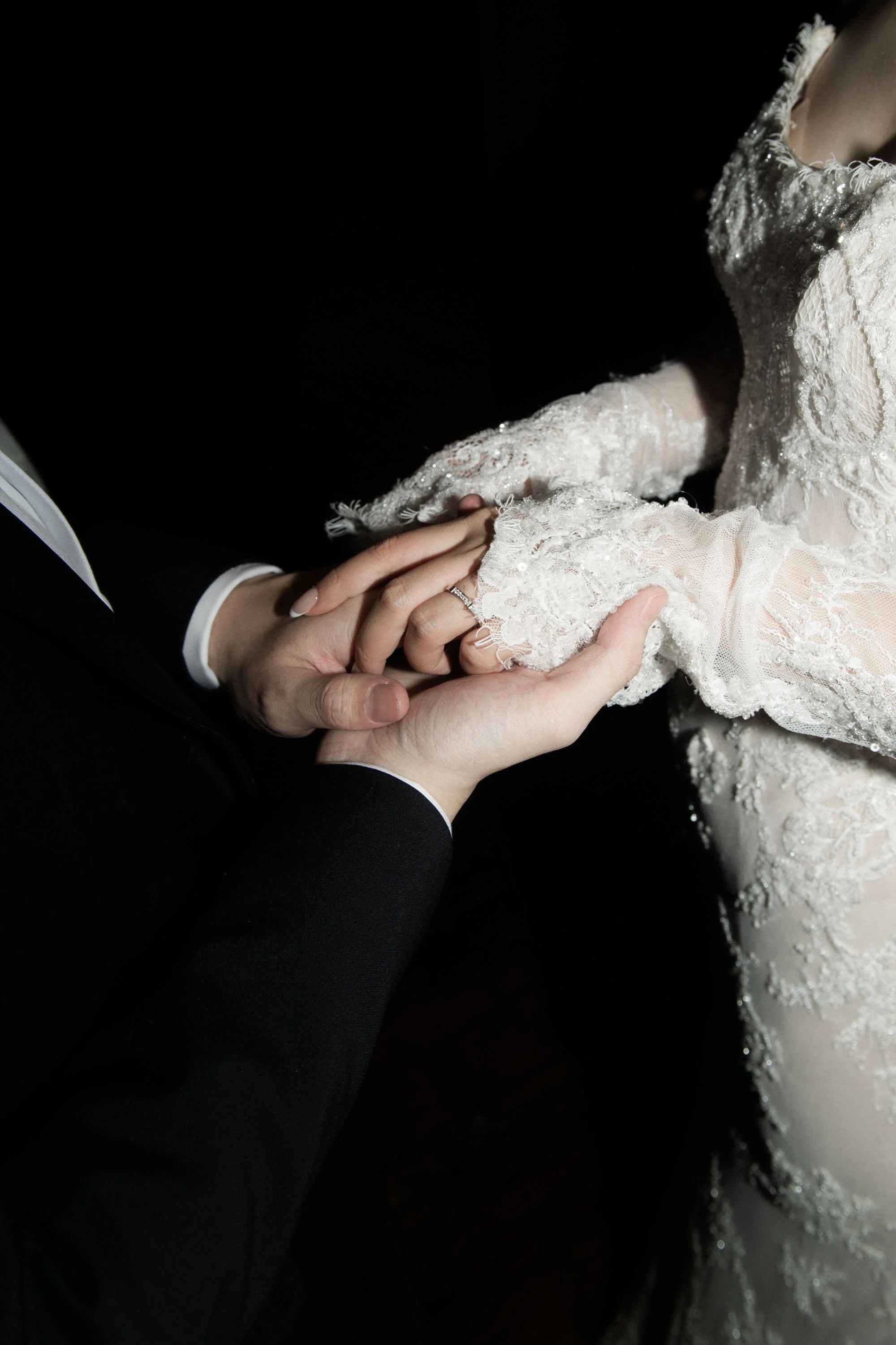 Close-up of the bride and groom holding hands before the reception entrance.