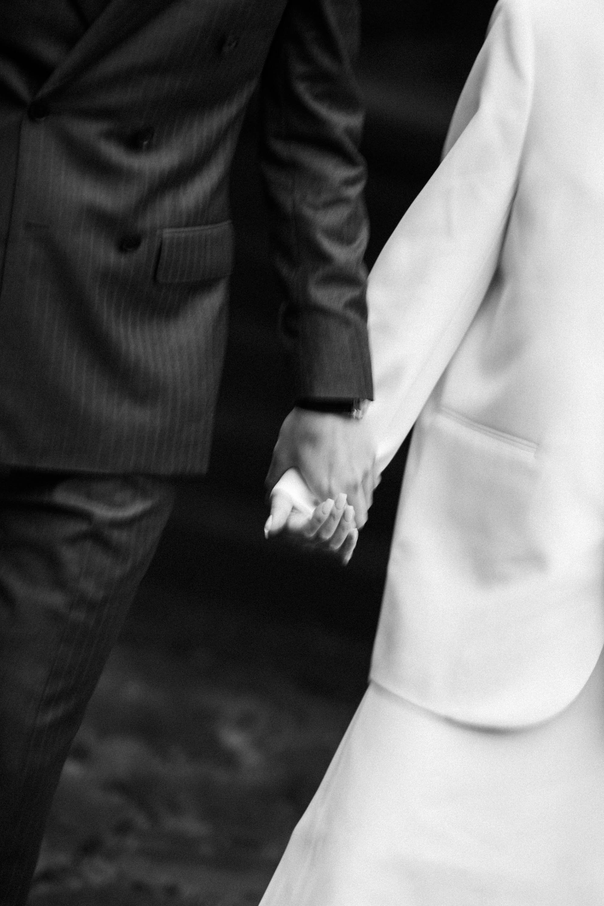 Close-up of the bride and groom holding hands.