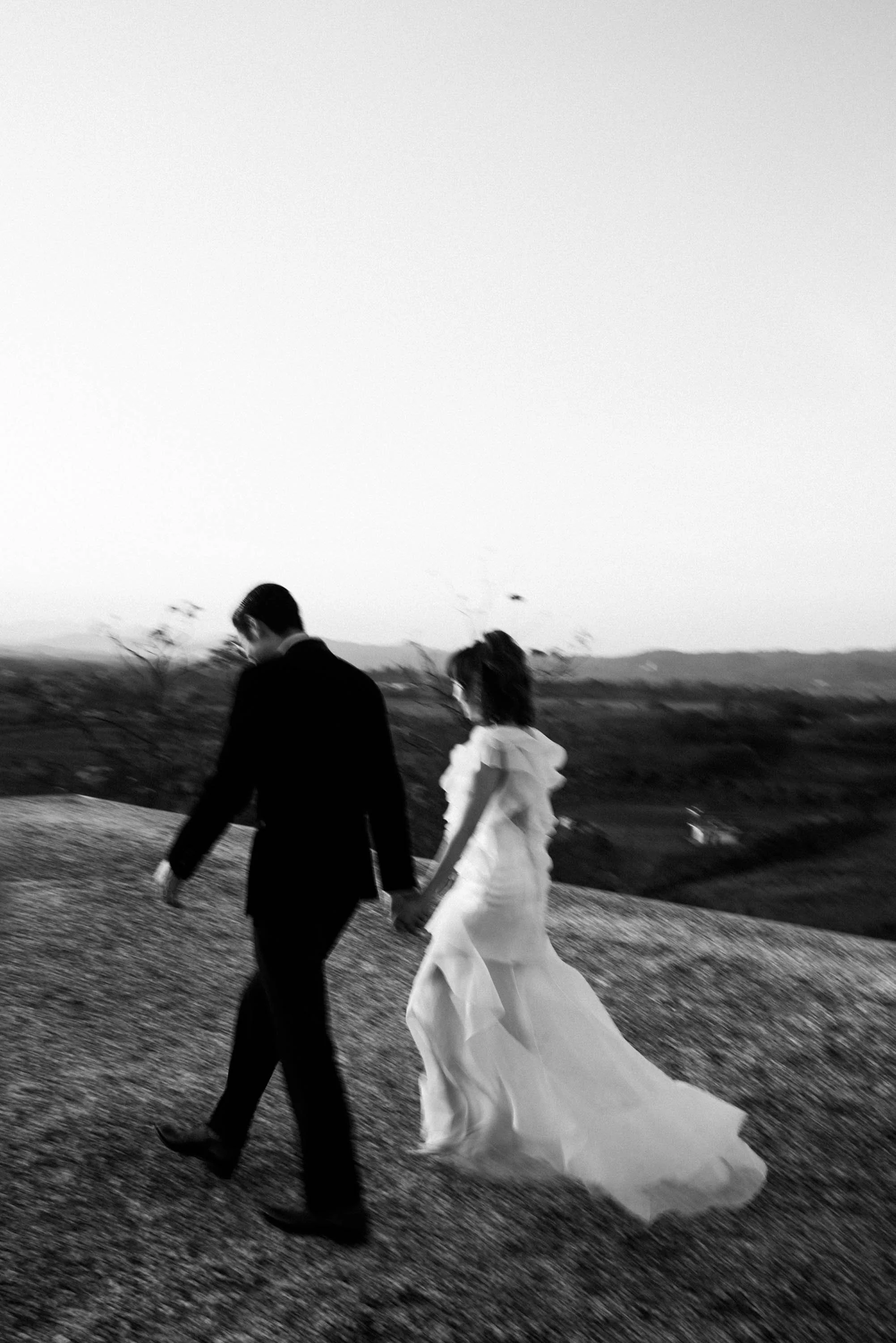 Bride and groom walking together on the rooftop during the evening.