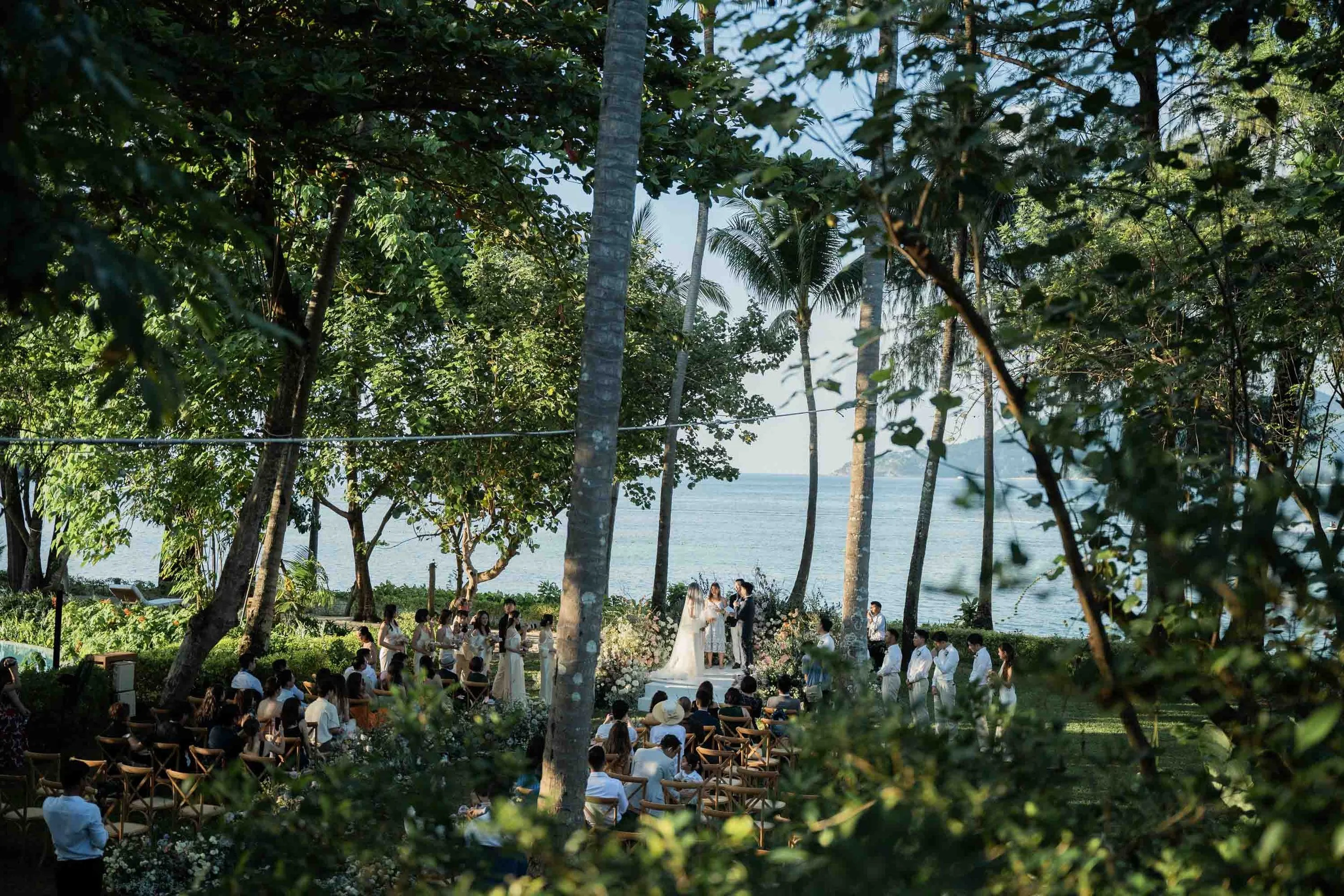 Bride and groom exchanging vows during an outdoor wedding ceremony at Rosewood Phuket.