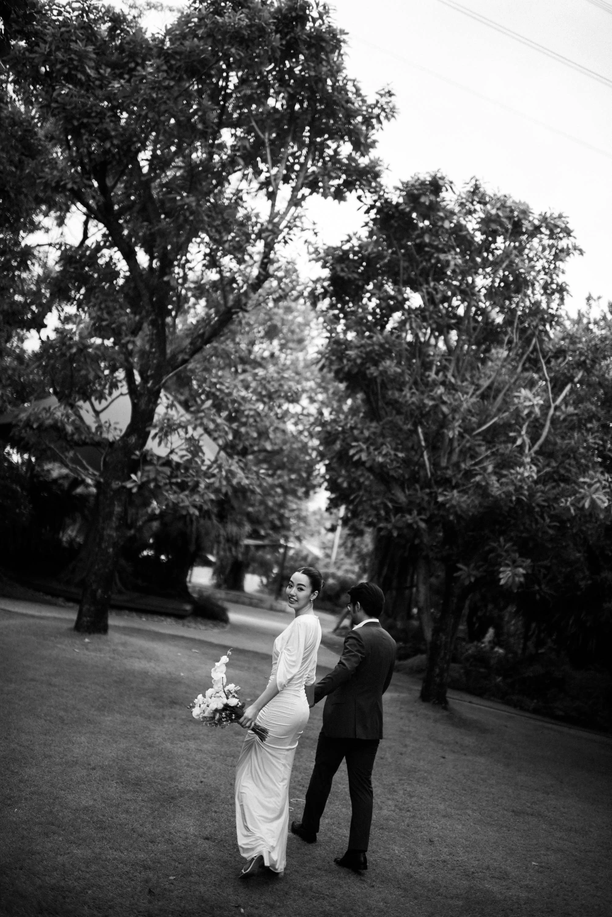 Couple walking through the garden as the woman turns back and smiles at the camera.