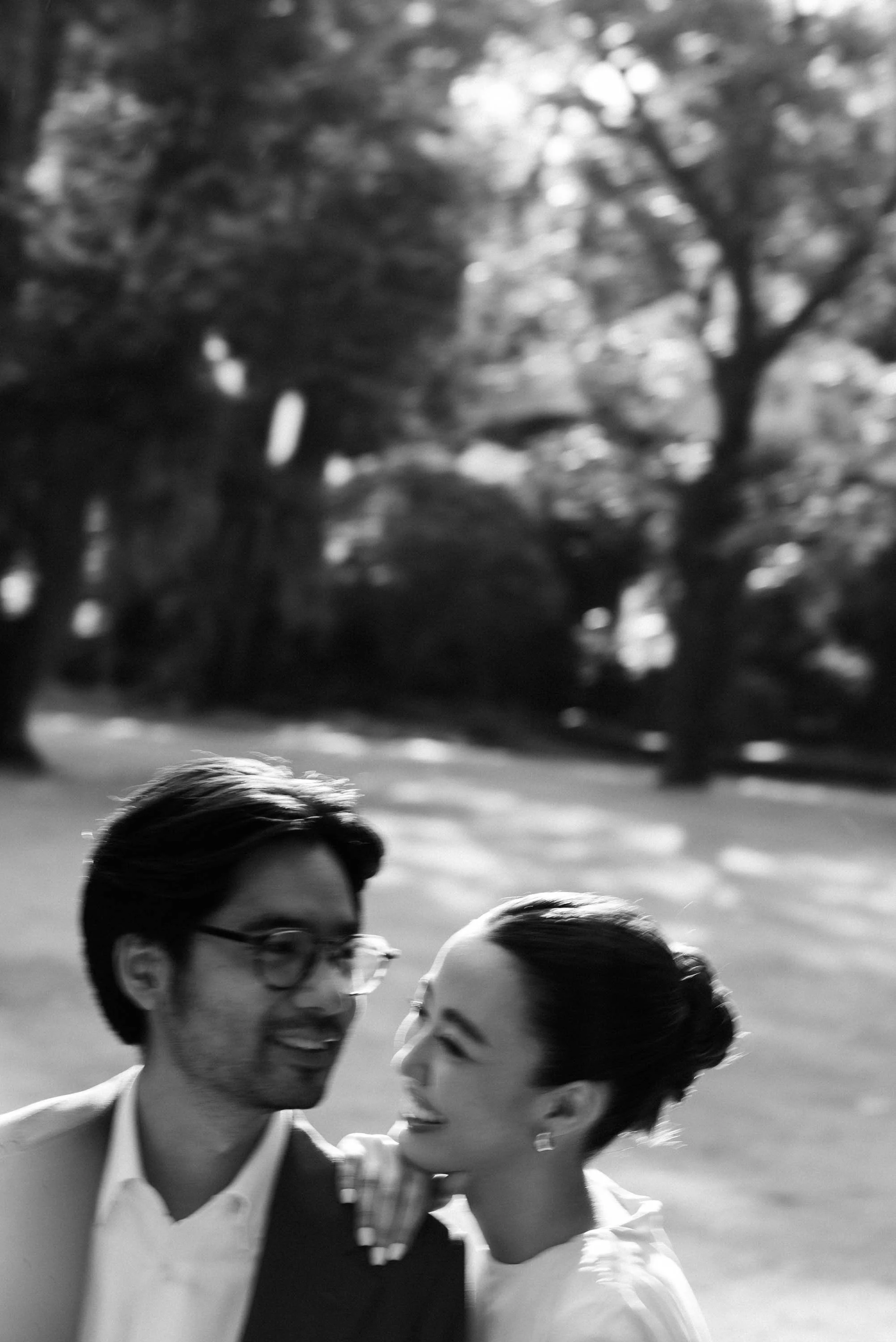 Woman resting her chin on her partner's shoulder as they walk through the garden.