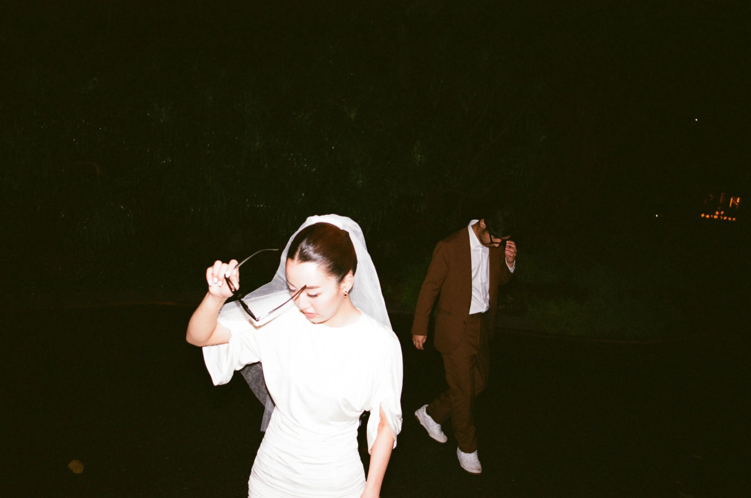 Couple standing together as they put on sunglasses for a playful portrait.