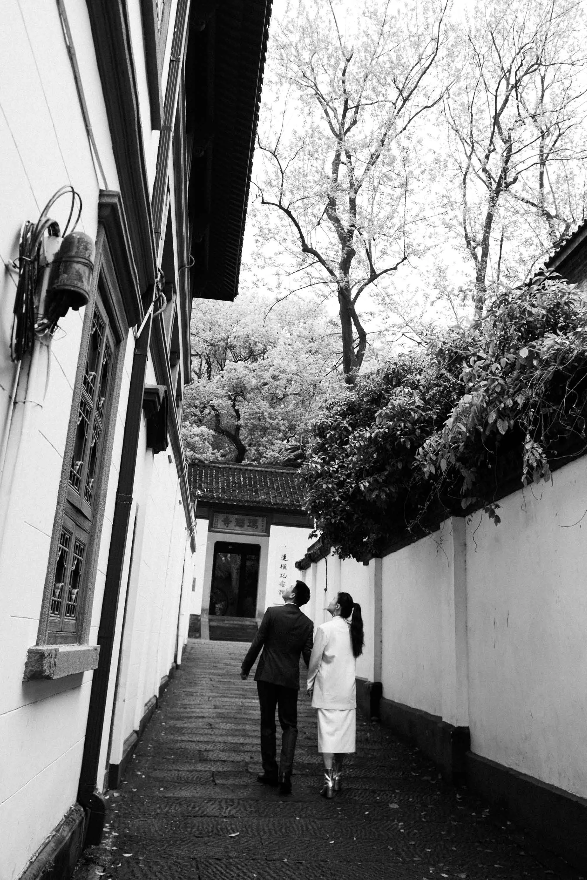 Bride and groom walking through a historic garden in Hangzhou.