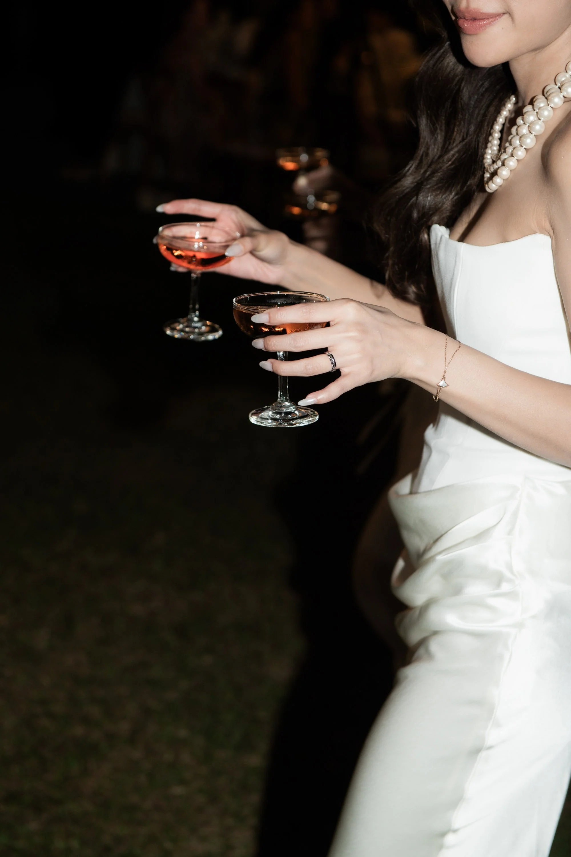 Bride holding a cocktail during the evening celebration.