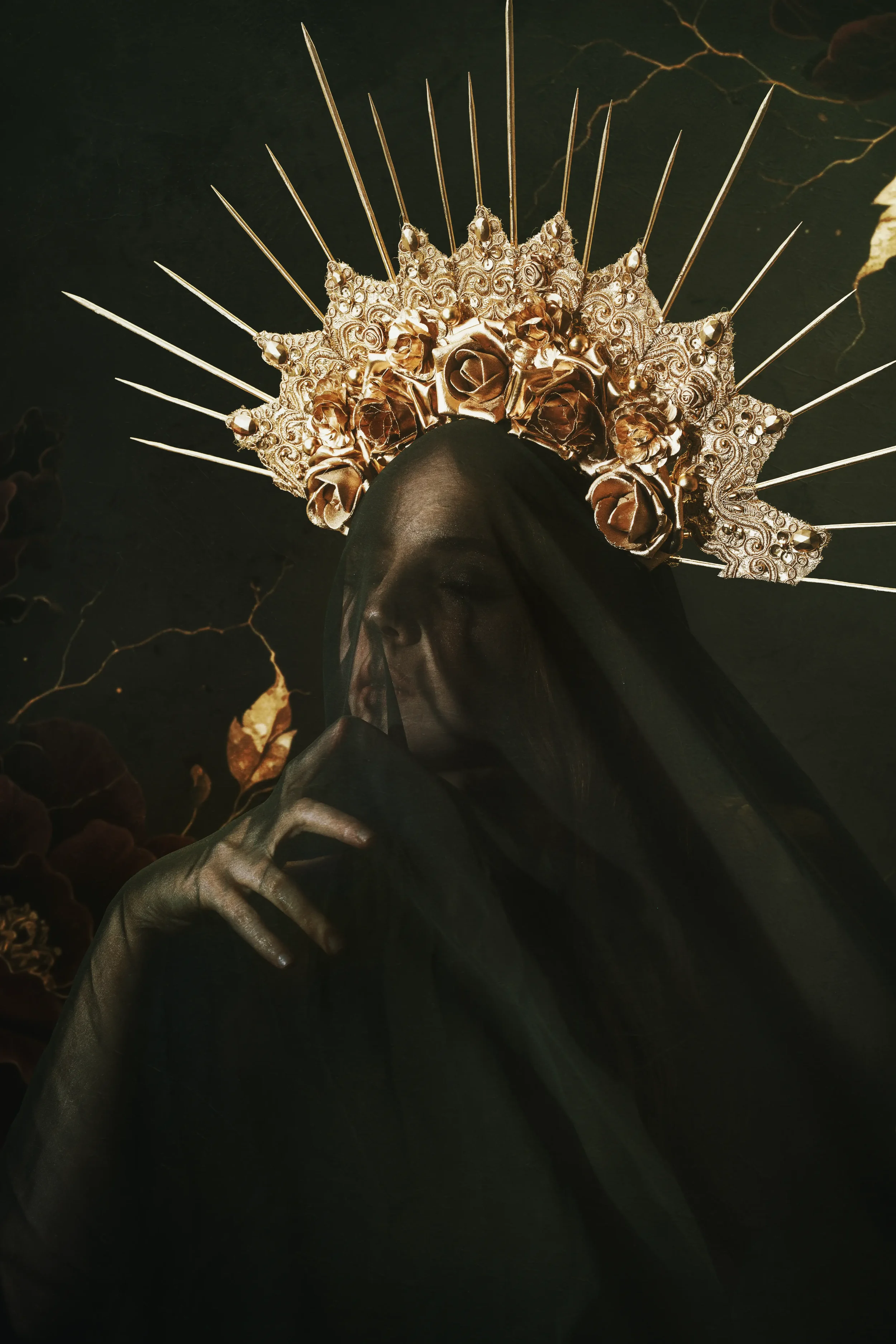 Fine art portrait of a veiled woman beneath an ornate gold crown with roses and radiant spikes against a dark floral background.