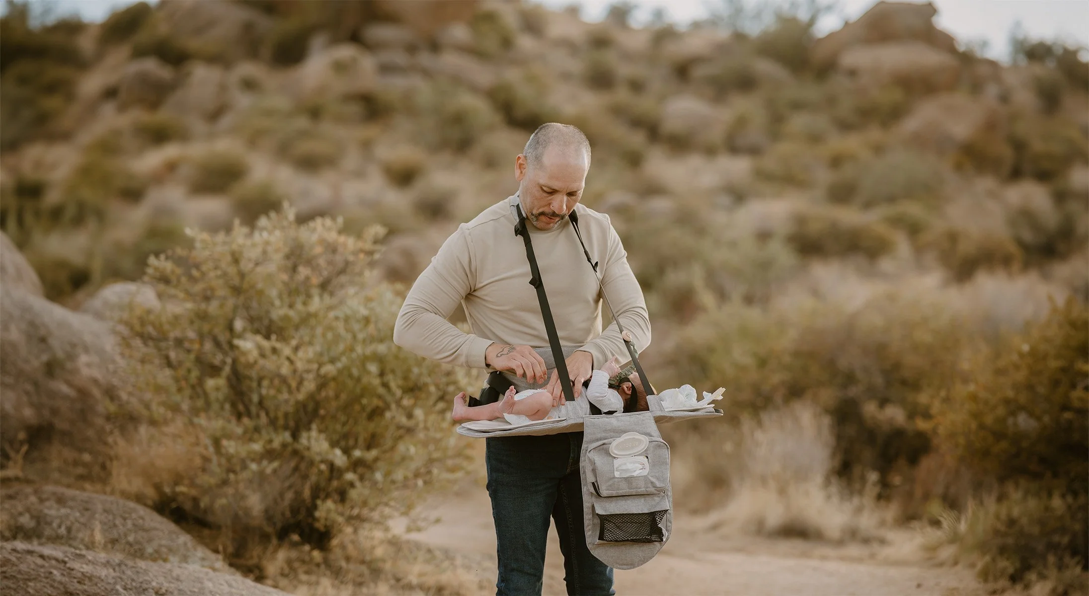 A man in outdoor clothing carrying a baby in a baby carrier.