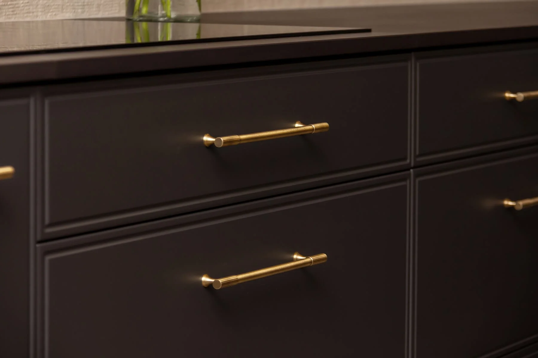Close-up of dark kitchen drawers with brass handles.