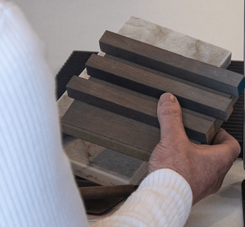 Hand comparing timber and stone samples for a joinery project.