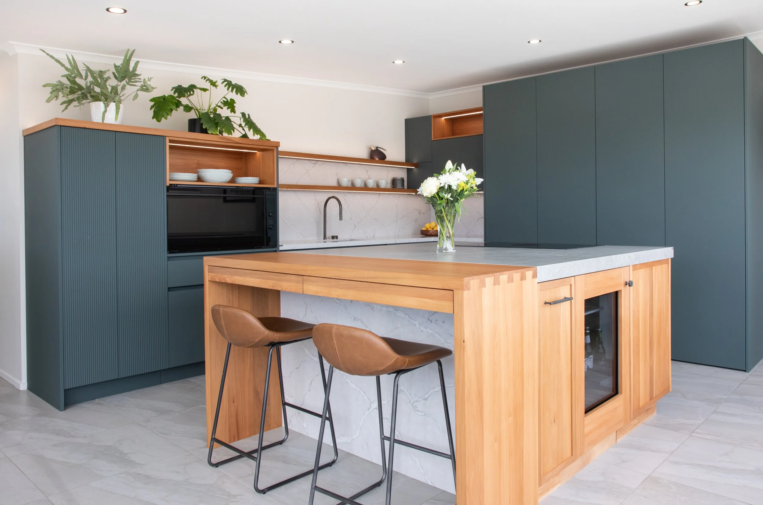 Modern kitchen with dark cabinetry, timber island and stone benchtops.