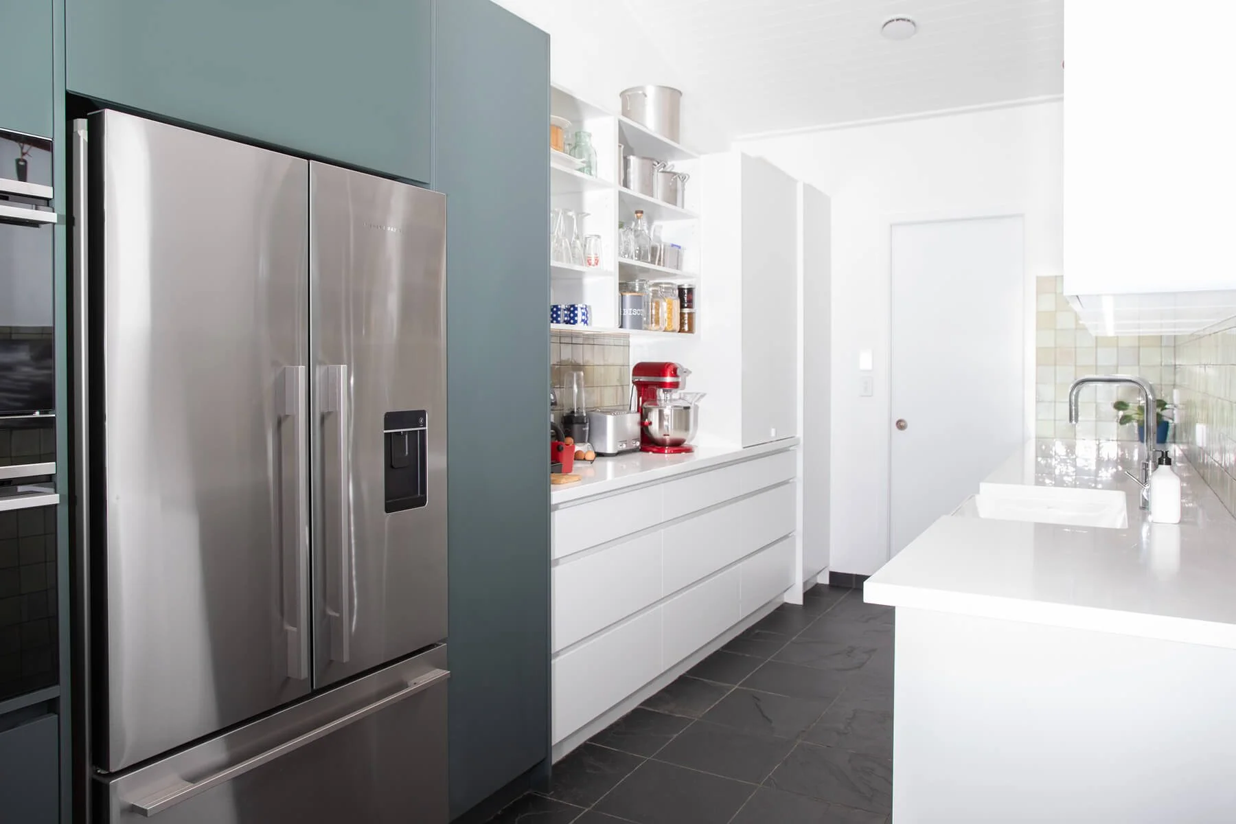 White scullery with open shelving, integrated fridge and generous drawer storage.