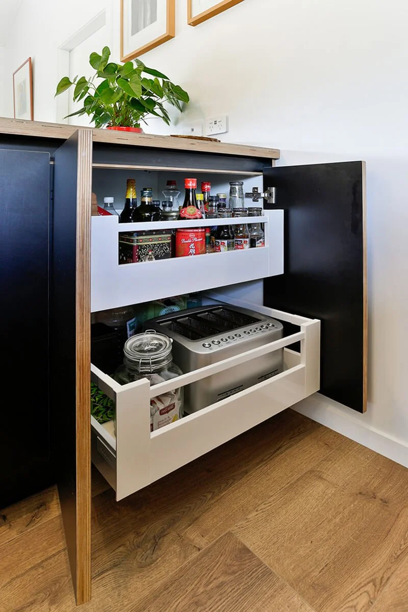 Pull-out drinks cabinet with organised storage for bottles and glassware.