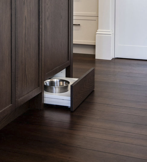 Integrated pet bowl drawer built into dark timber cabinetry.
