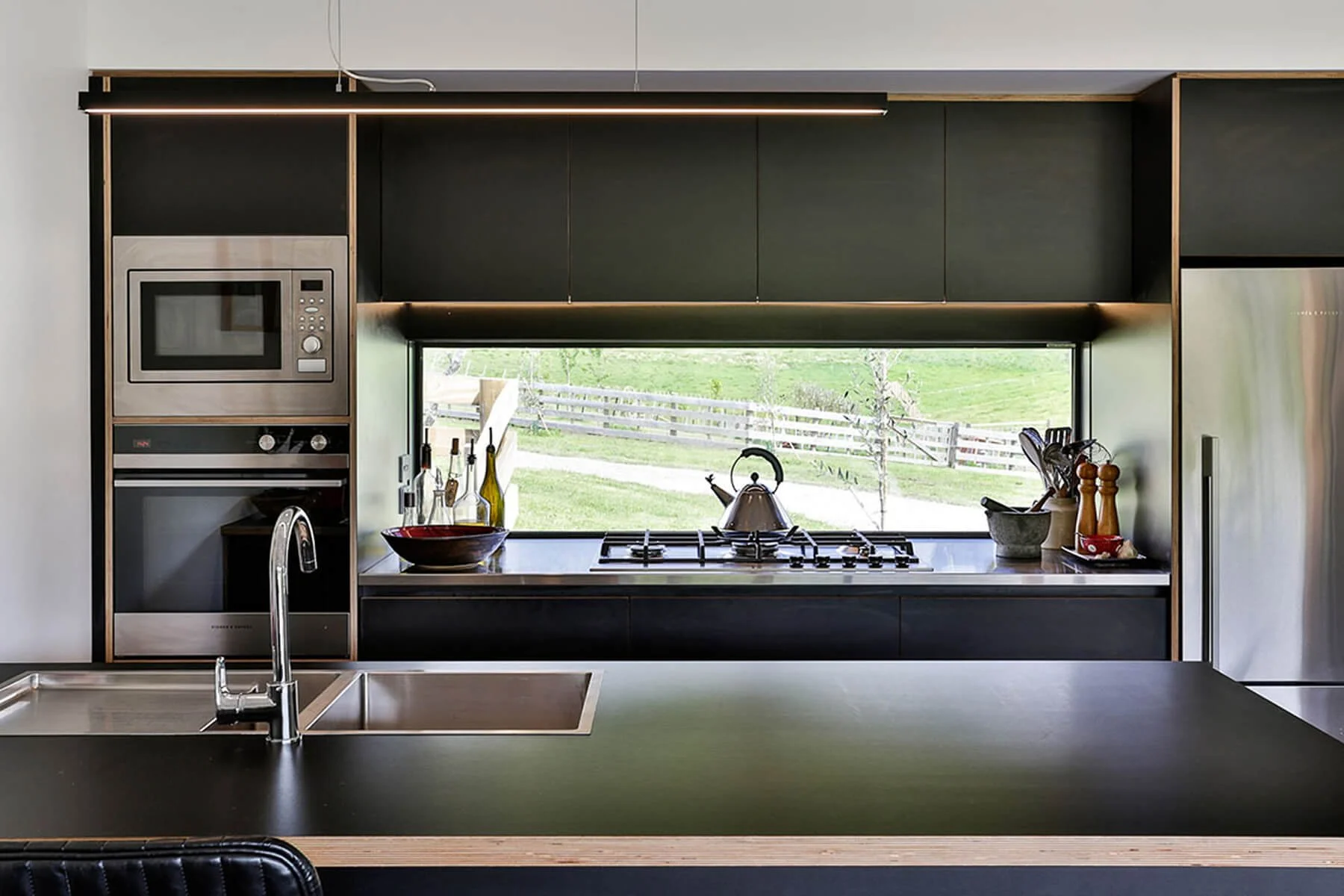 Dark contemporary kitchen with wide picture window overlooking the countryside.