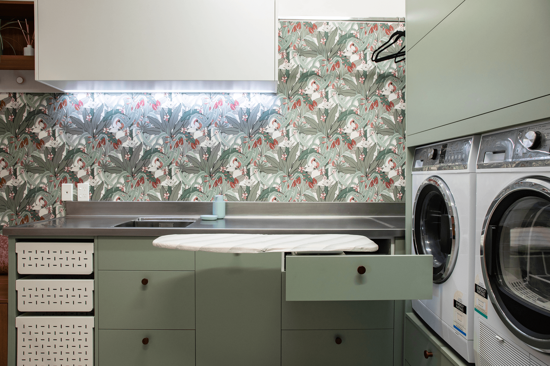 Sage green laundry with integrated ironing board, washer and dryer.