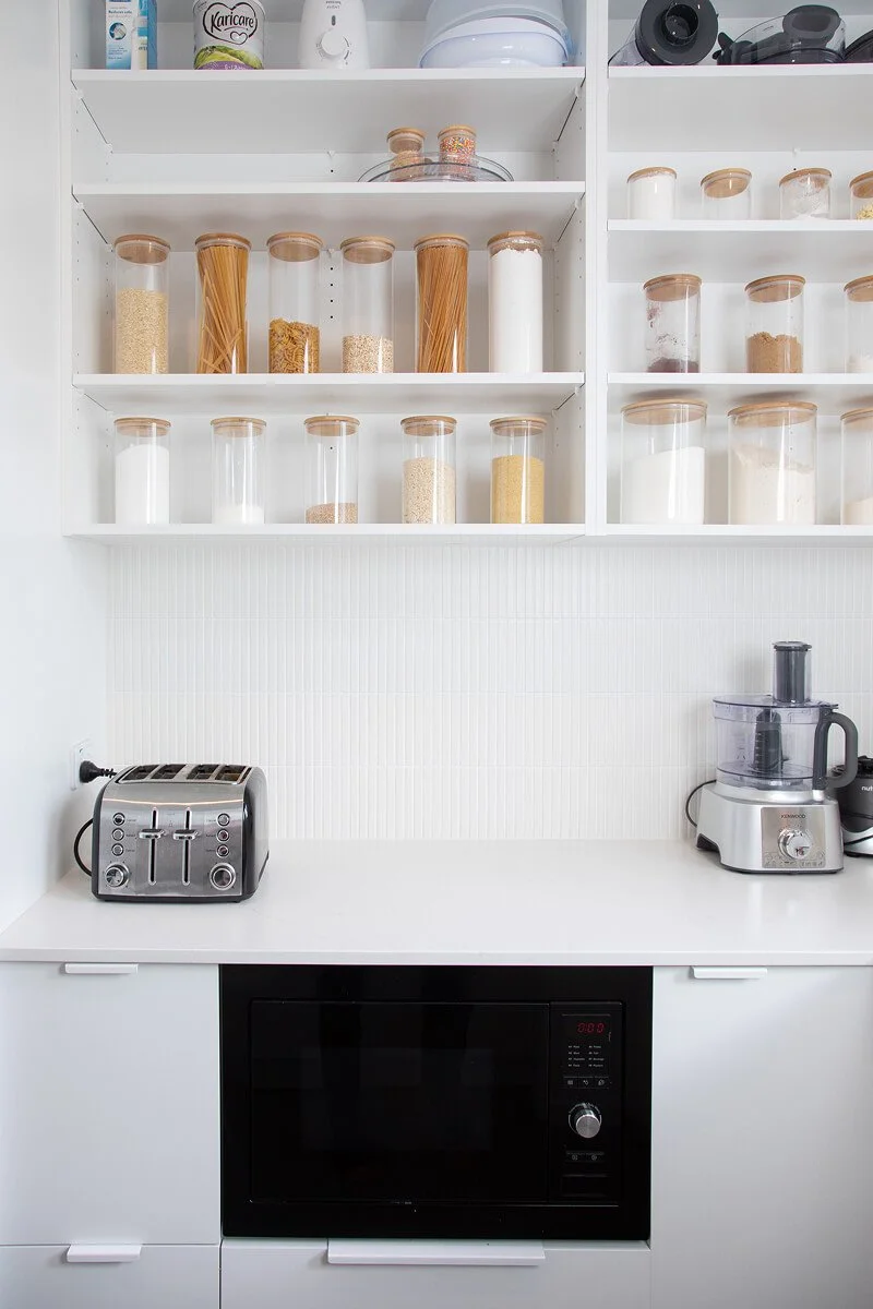 Scullery with open pantry shelving, integrated microwave and organised dry food storage.