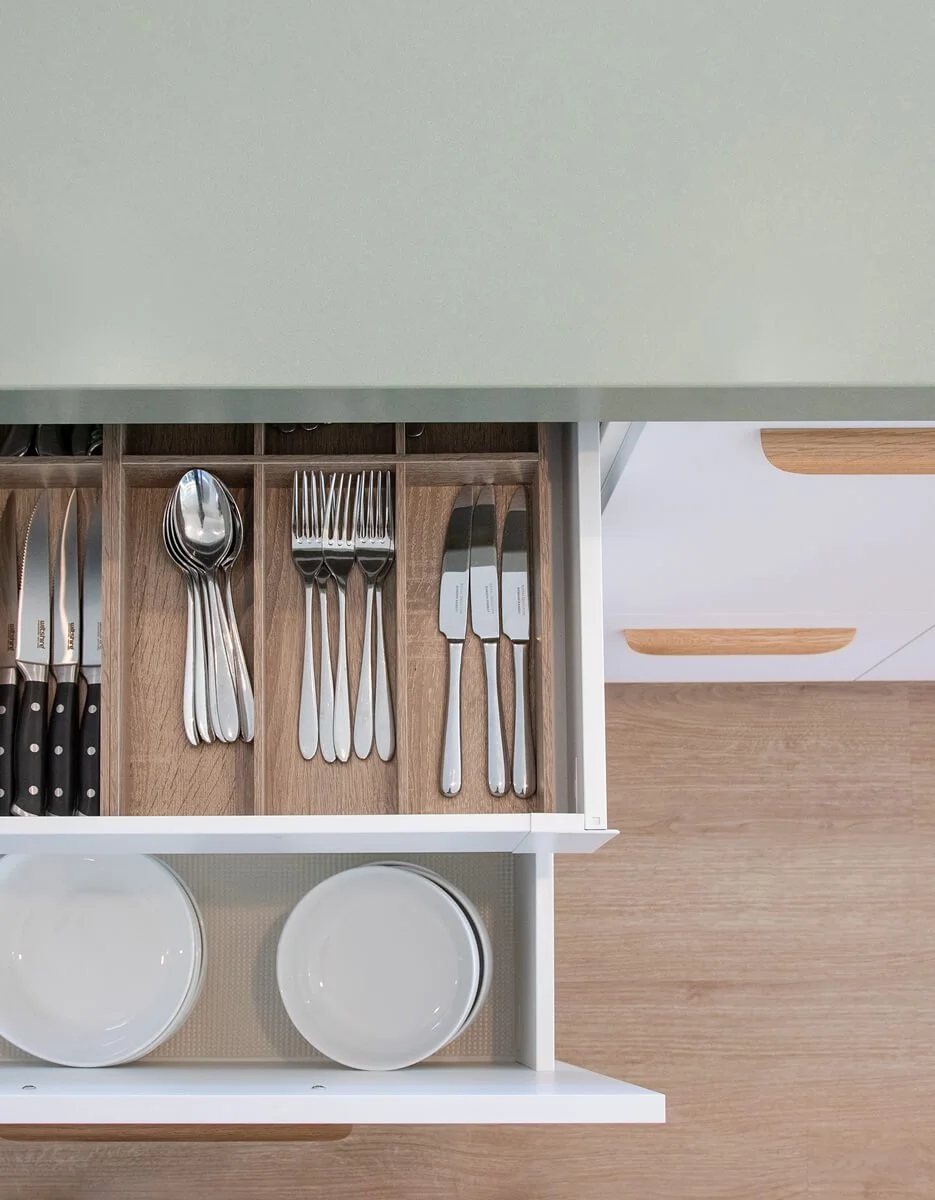 Kitchen drawer with timber cutlery organiser and pull-out plate storage.