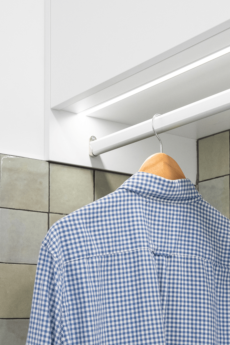 Integrated laundry hanging rail with shirt and under-cabinet lighting.