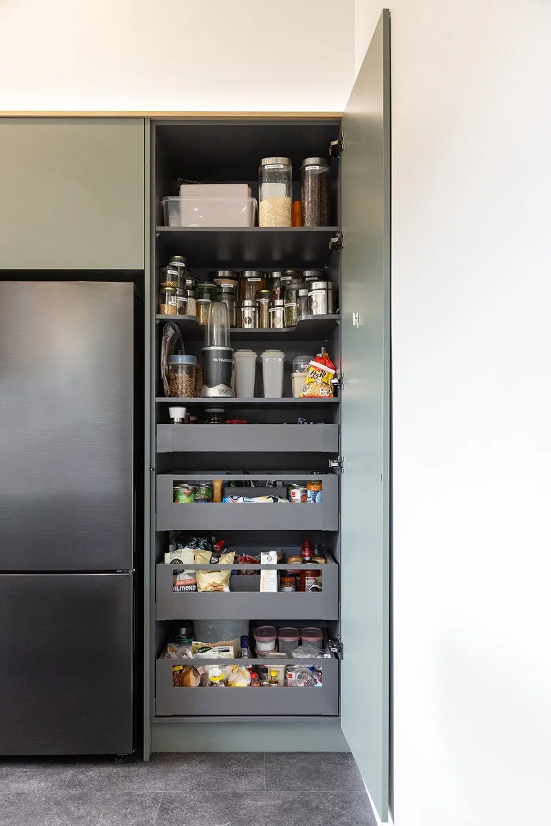 Tall pull-out pantry with organised storage for spices, jars and dry food.