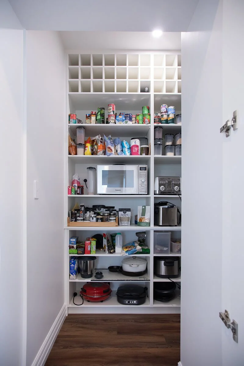 Walk-in pantry with open shelving for food, appliances and cookware.