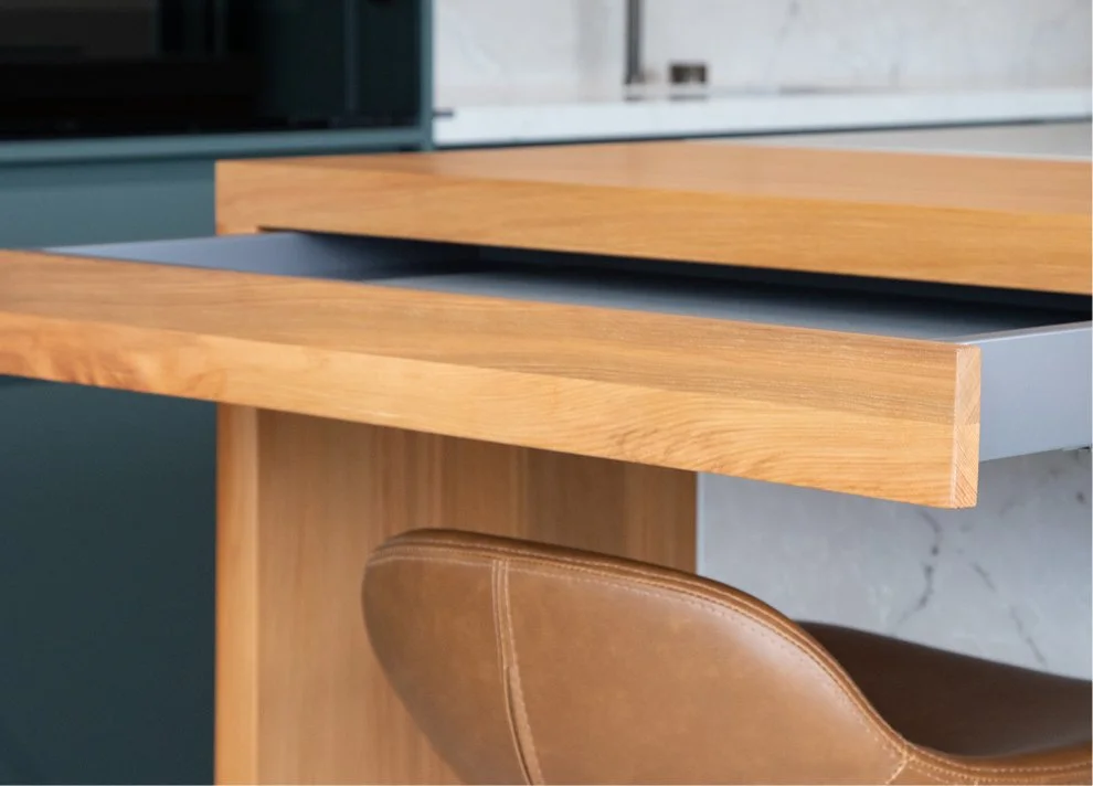 Close-up of a timber kitchen island with integrated pull-out work surface.