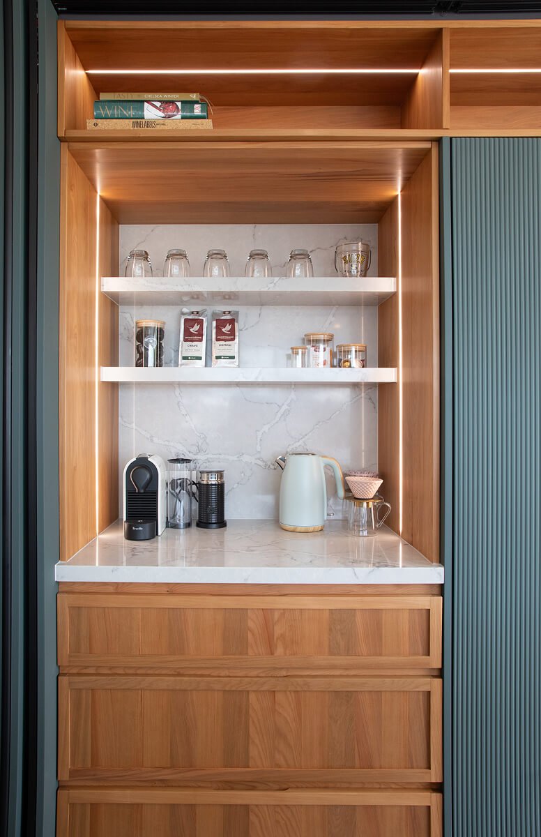 Built-in coffee station with timber cabinetry, stone surfaces and integrated lighting.