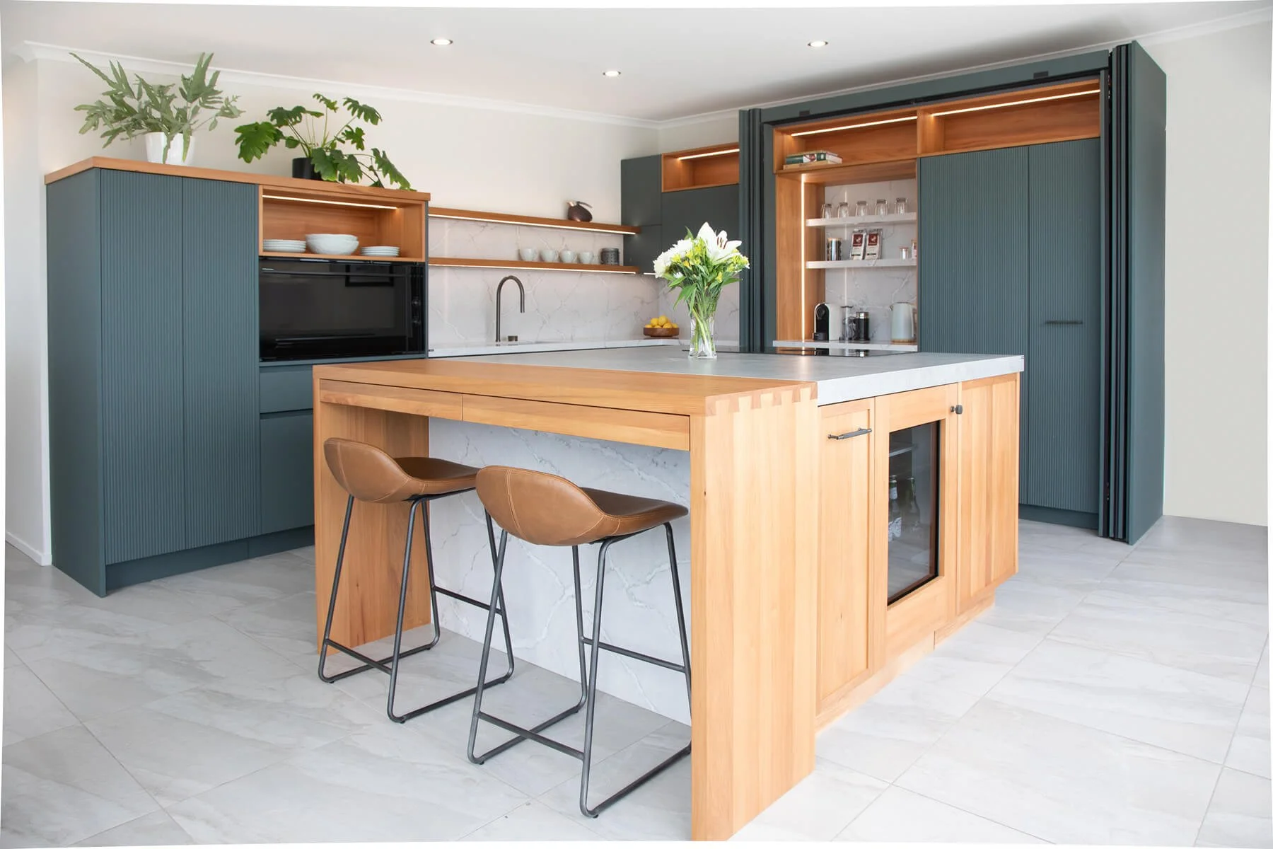 Bespoke kitchen with timber island, dark green cabinetry and integrated storage.