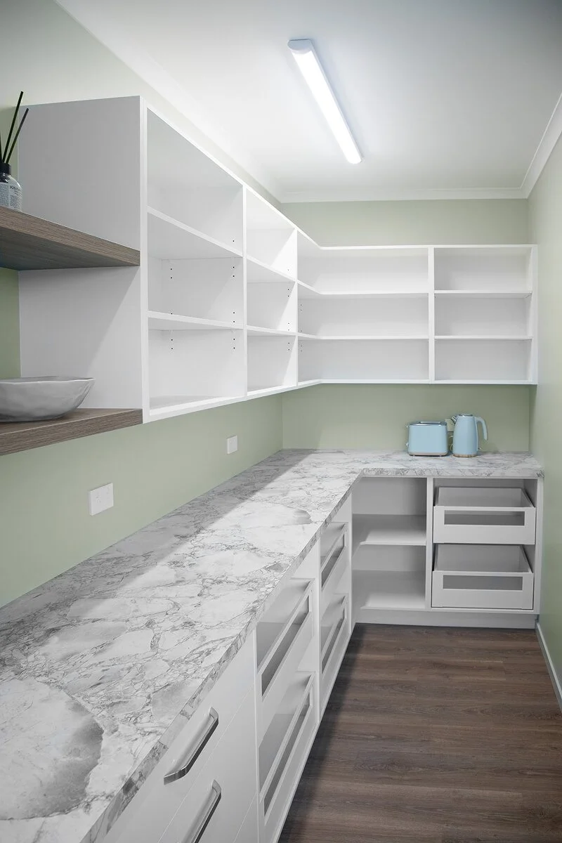 Walk-in scullery with open shelving, stone benchtops and generous storage.