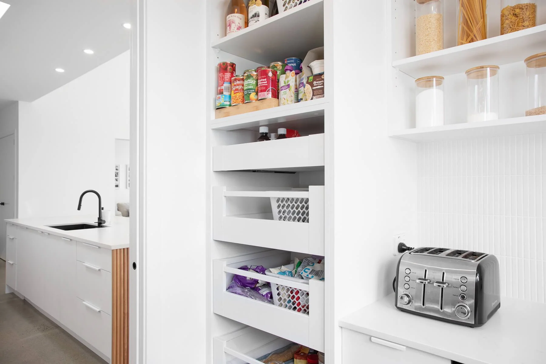 Pull-out pantry drawers with organised food storage beside the scullery worktop.