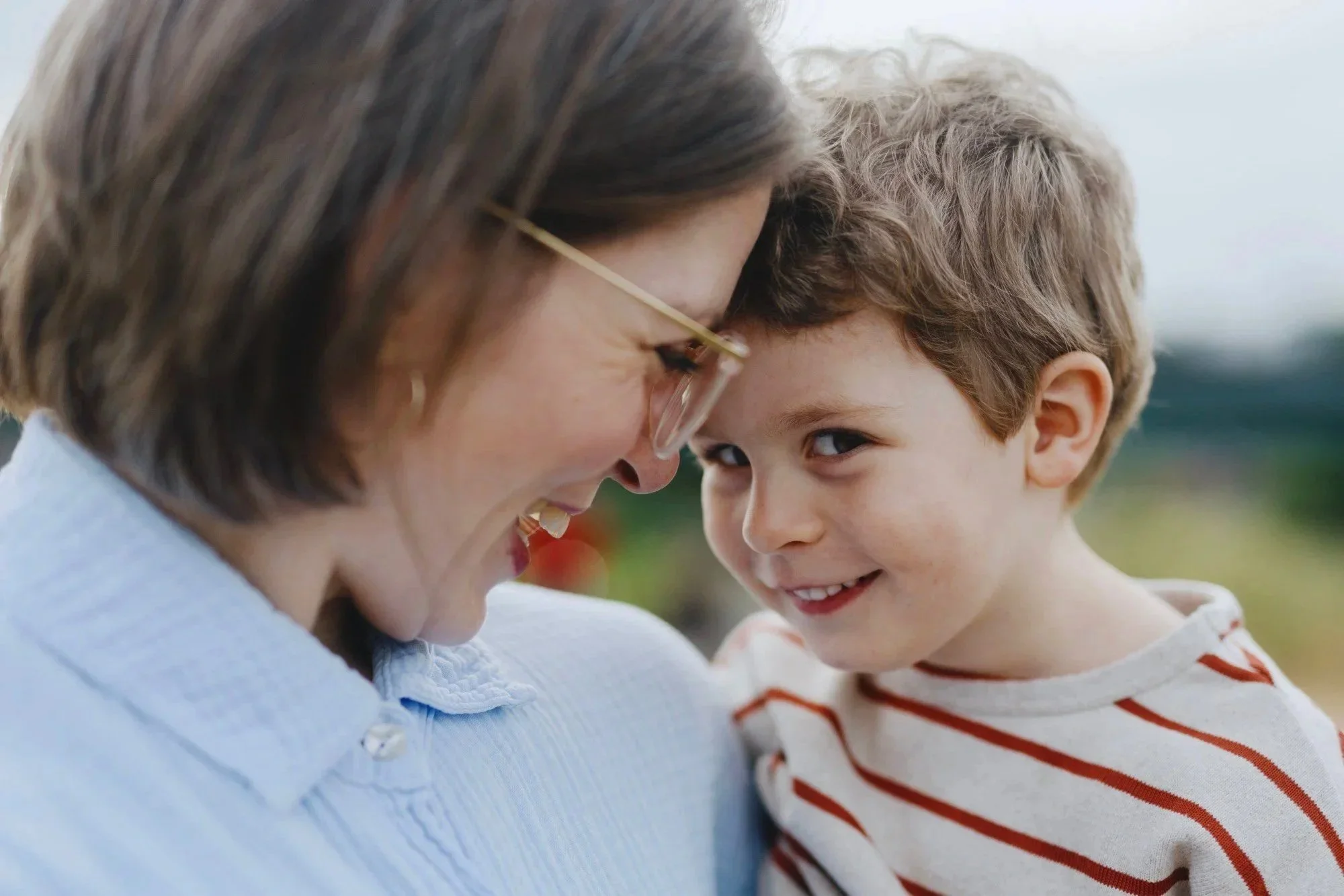 Mutter und Sohn Stirn an Stirn, sie lachen zusammen.