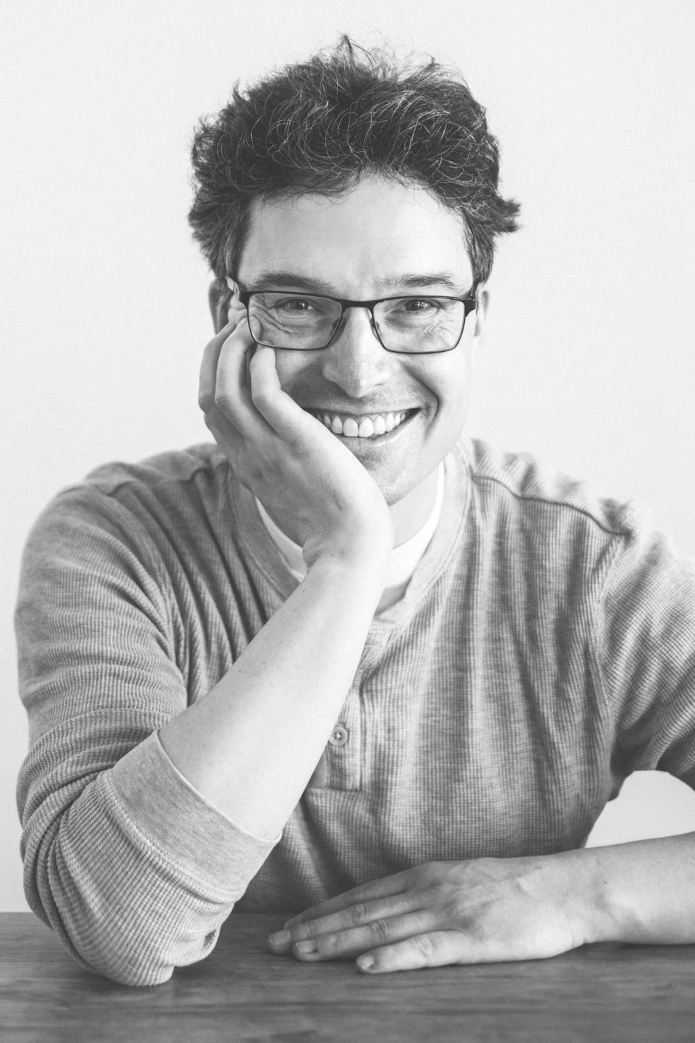 Schwarz-weiß Bild von Niels Herrmann, Fotograf, mit Brille und Lächeln