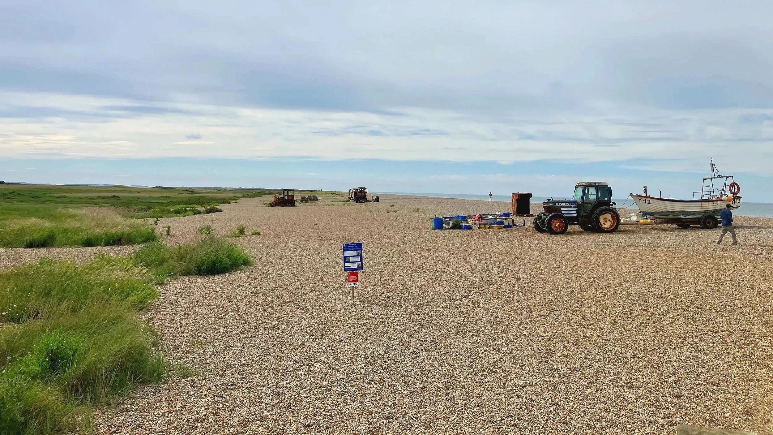 Shingle beach at Cley with a tractor and fishing boat, looking towards Blakeney Point