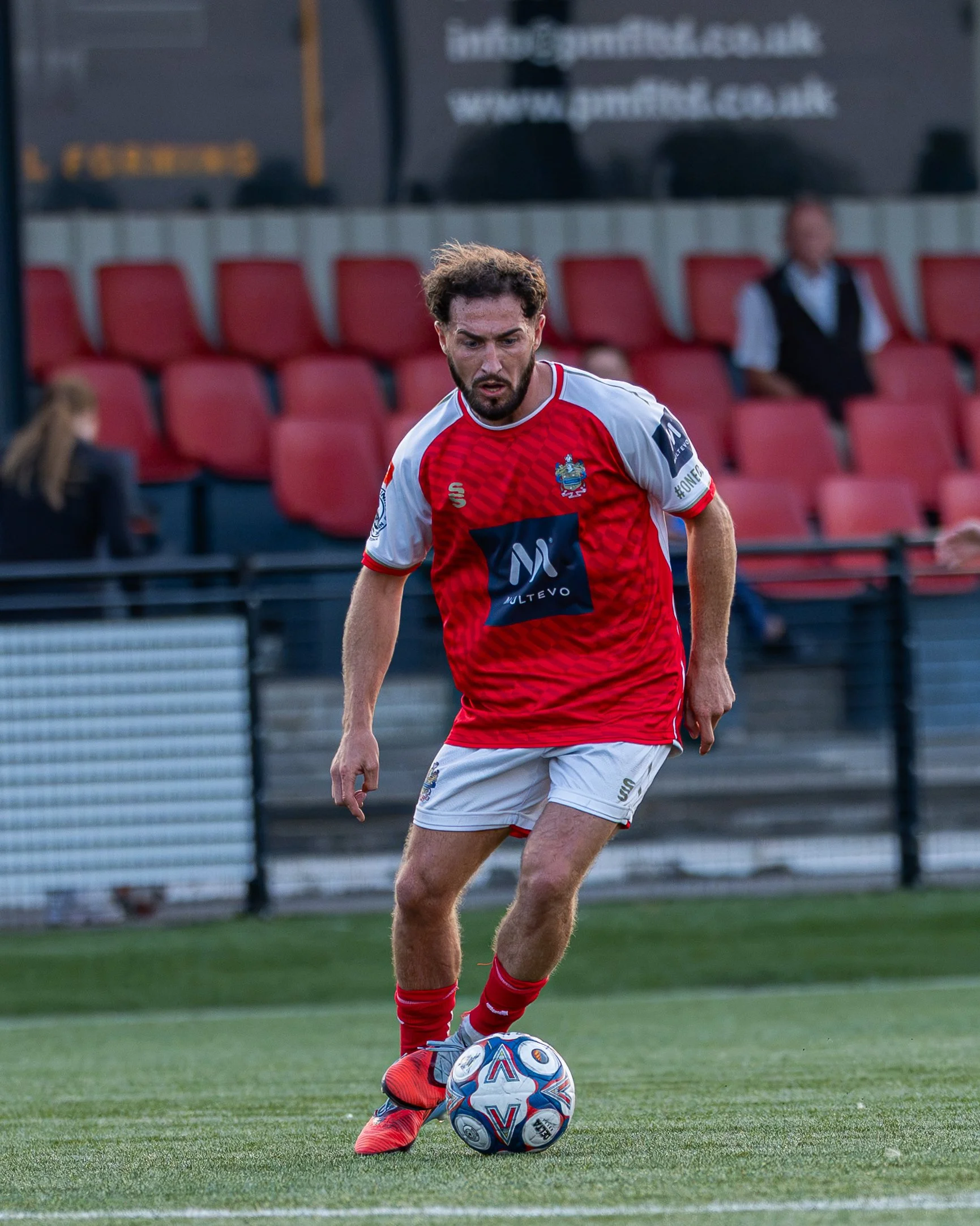 A soccer player in a red and white uniform dribbling a soccer ball on the field.