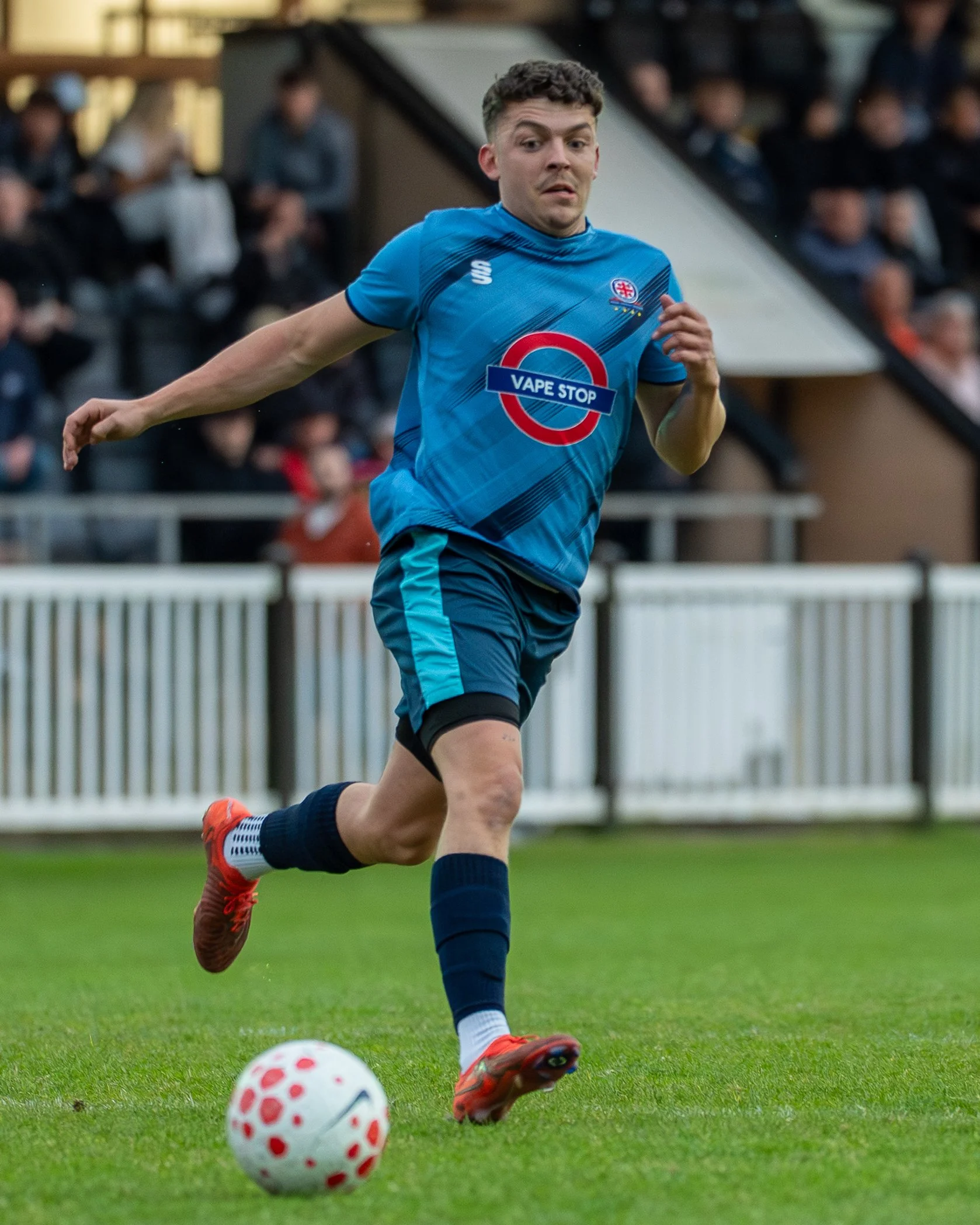A male soccer player in a blue uniform running on a soccer field during a match.
