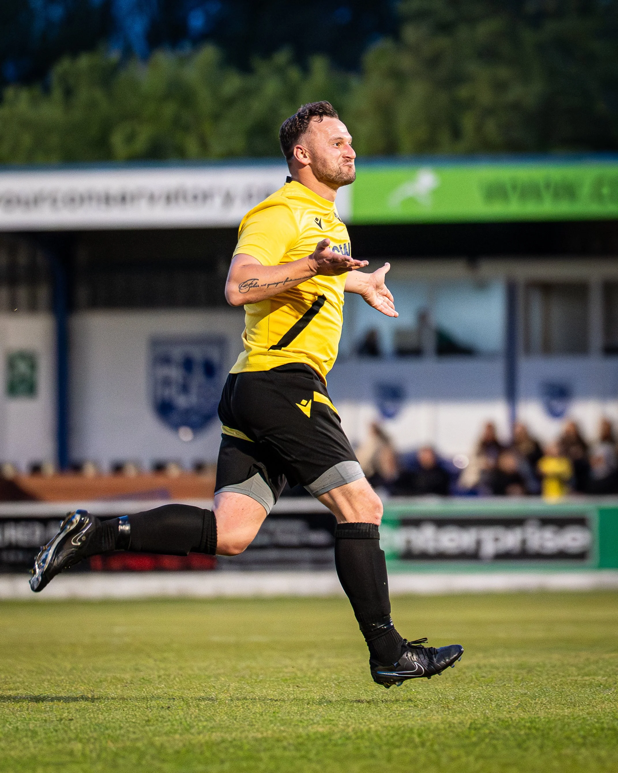 Soccer player wearing yellow jersey and black shorts running on the field