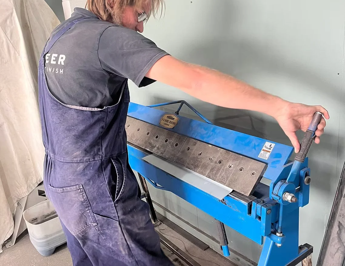 A person operating a blue tile cutter or glass cutter machine indoors.