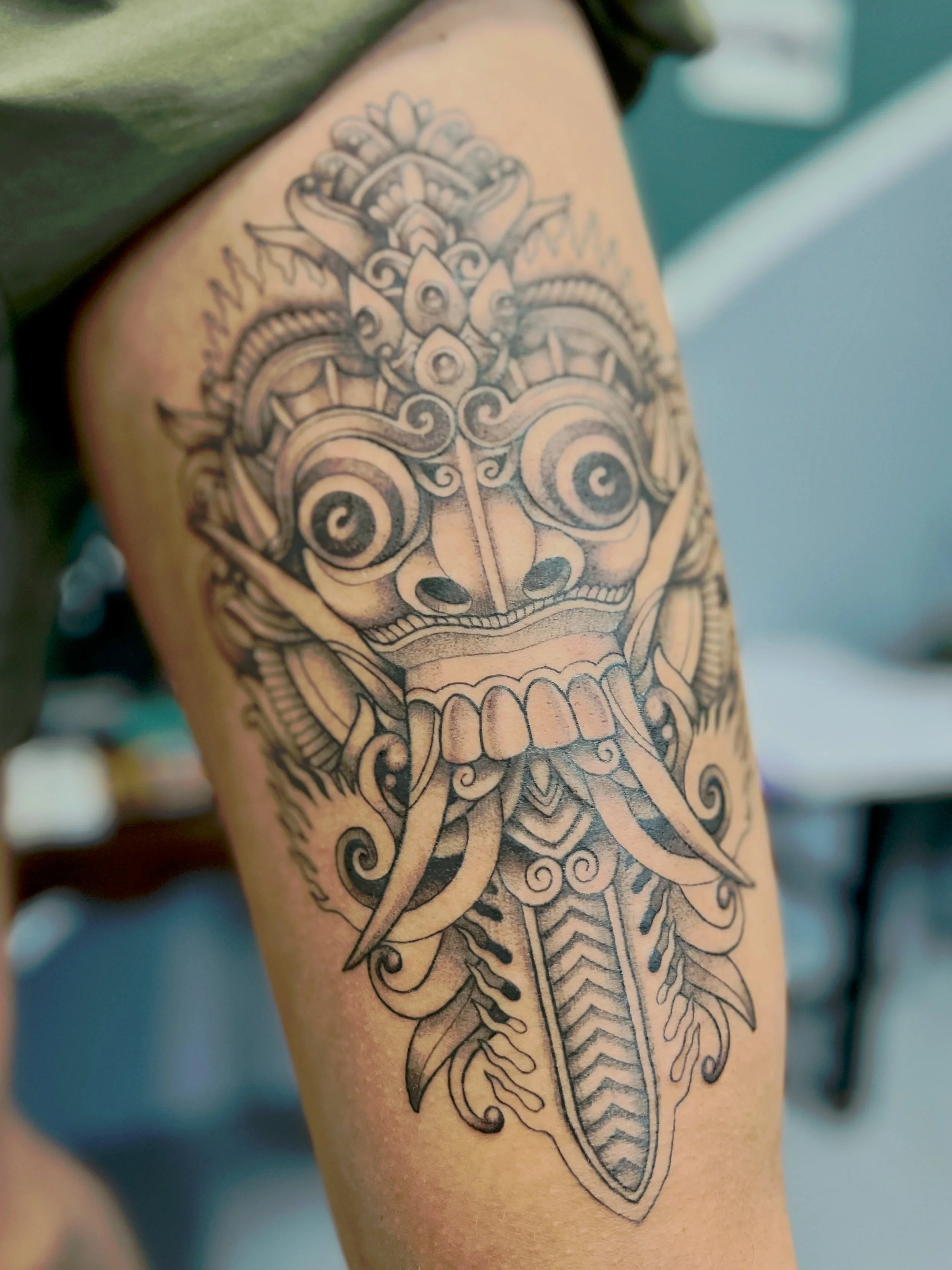 Een tatoeage van een schedel met ingewikkeld ontwerp op de bovenarm.