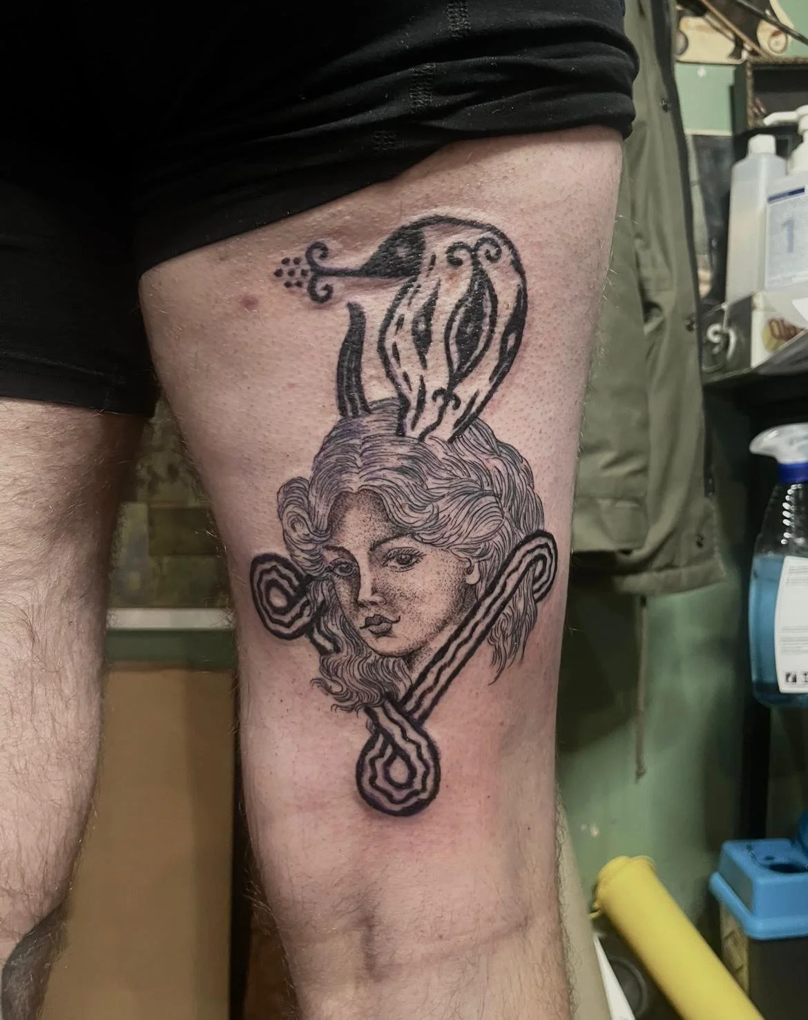 Tatoeage van een vrouw met golvend haar, met een slang die haar hoofd omringt, en een toverstaf met een ster boven haar hoofd.