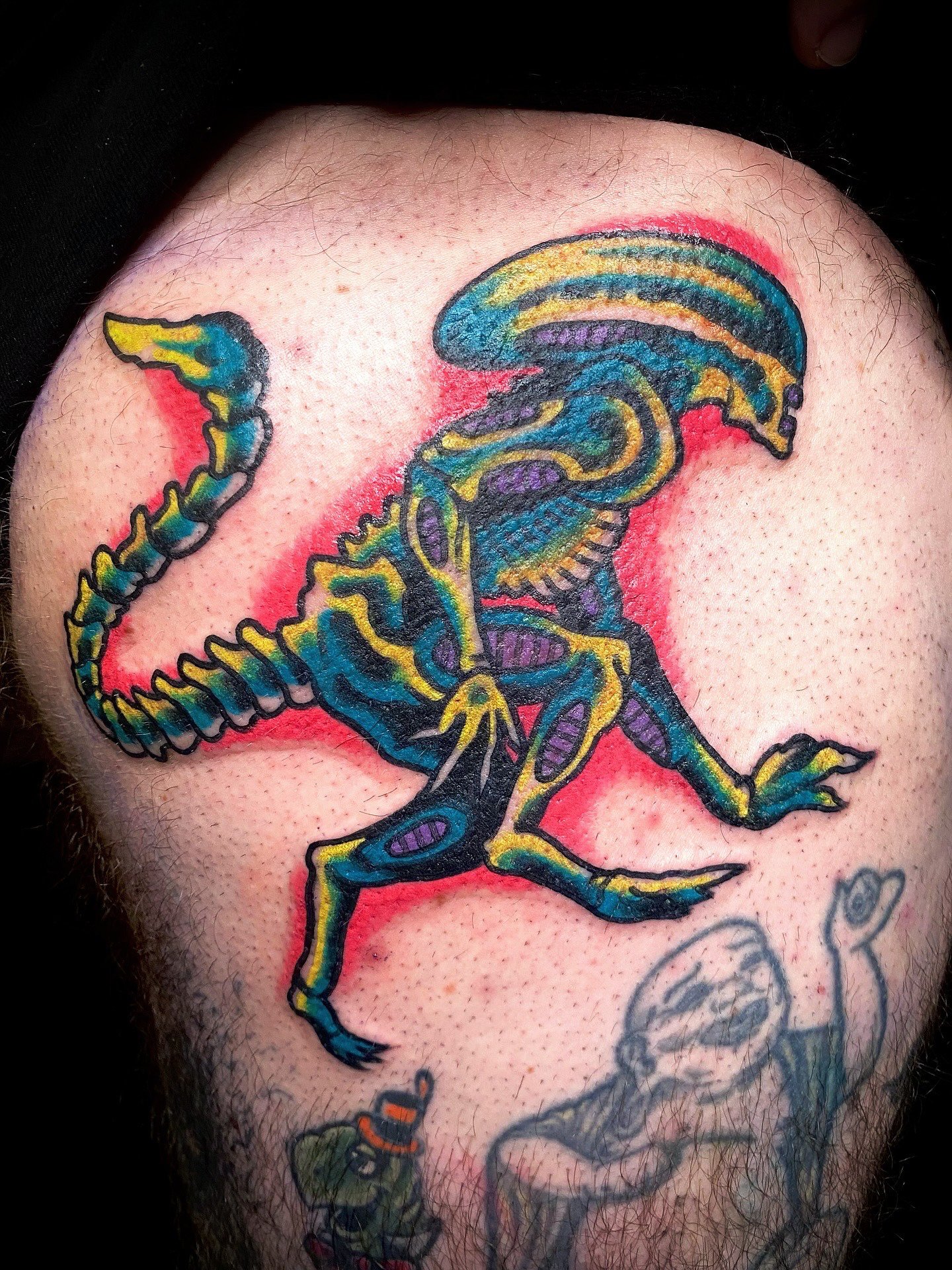 Kleurrijke tattoo van een dinosaurusskelet op een mensenarm.