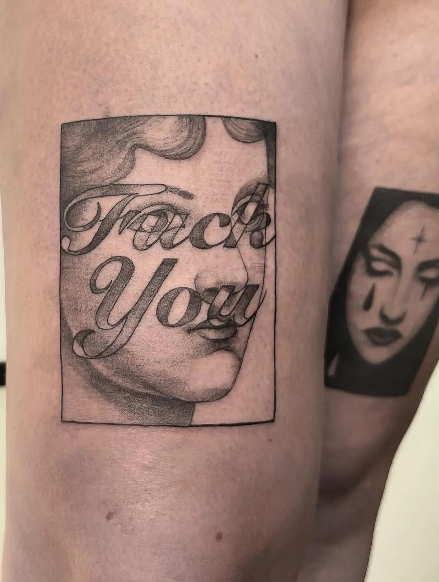 Tatoeage van een vrouw met grote wenkbrauwen en volle lippen, met tekst in gotische stijl.