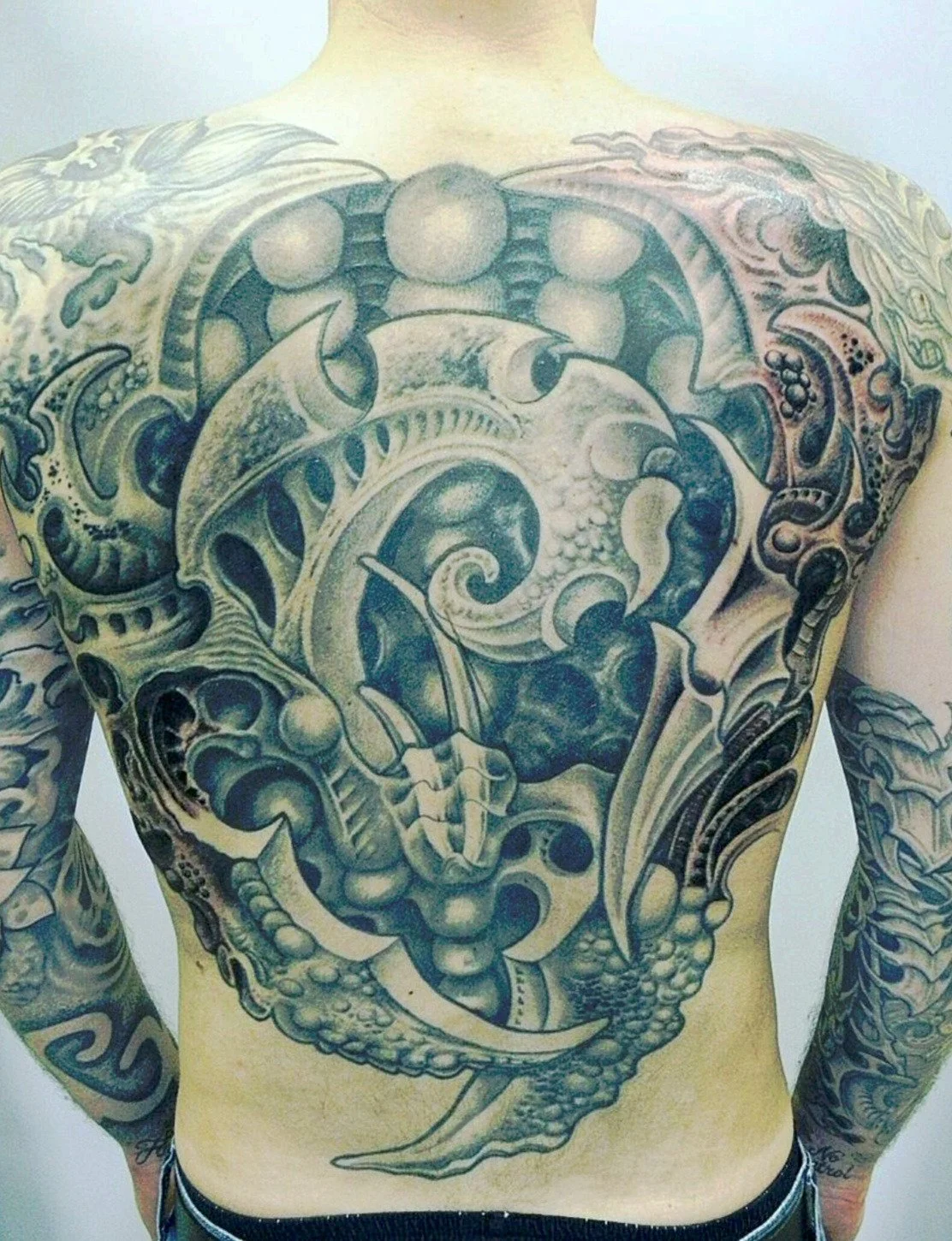 Een grote, gedetailleerde zwart-witte tatoeage op de borst, die een onderwaterwereld met een zeeschildpad, vissen, schelpen en waterplanten afbeeldt.