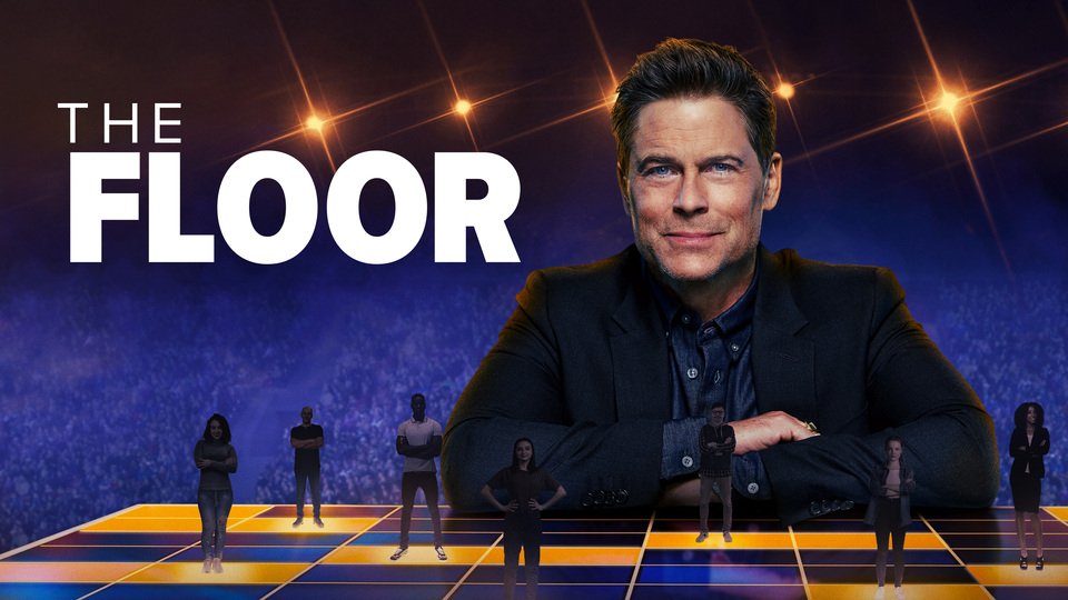 Promotional image for the game show 'The Floor', featuring a large man in a black suit sitting with arms crossed, with smaller people standing on a glowing game floor beneath him, and a dark background with bright star-like lights.
